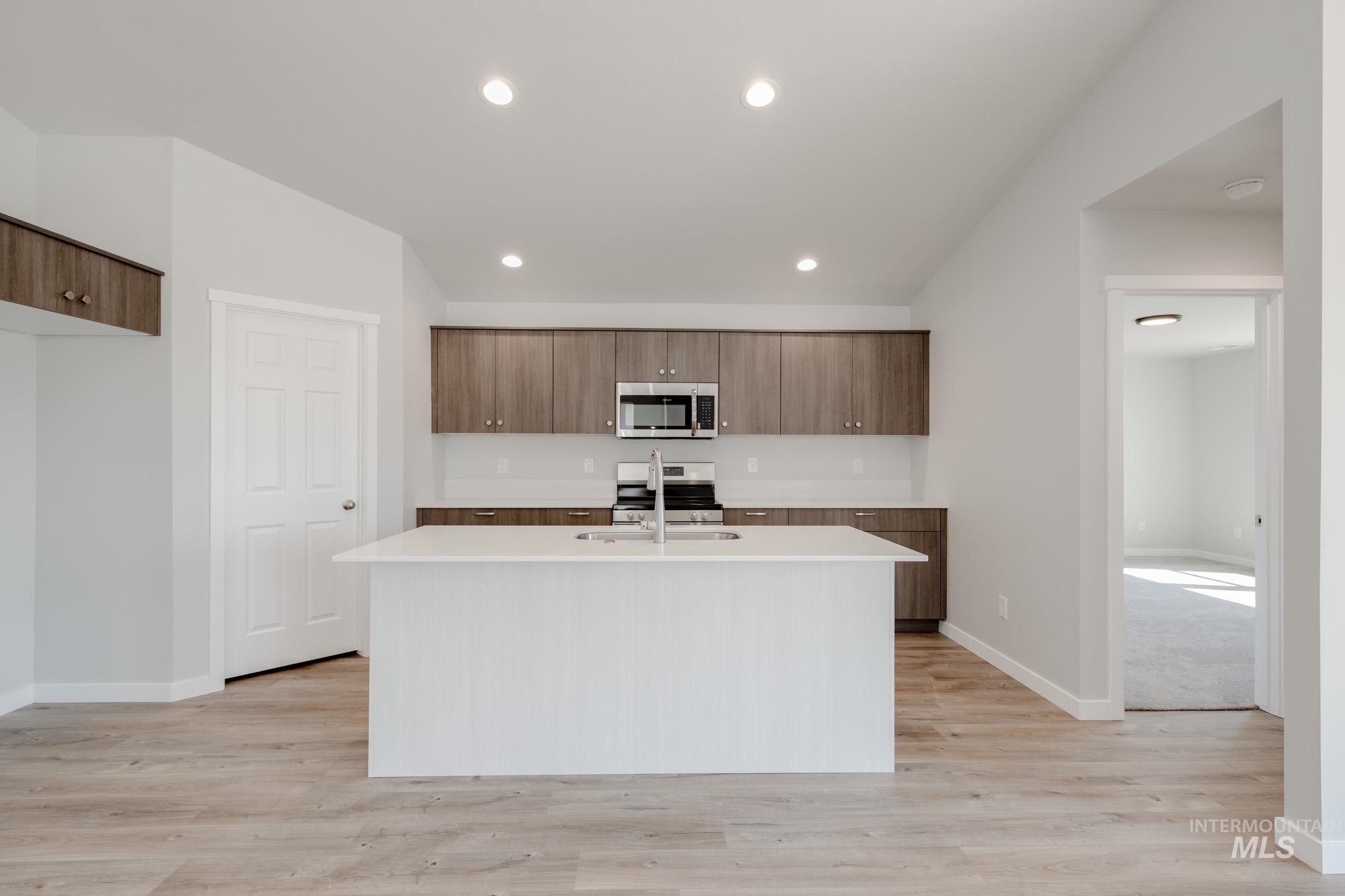 Kitchen with modern cabinets, stainless steel appliances, a center island with sink, recessed lighting, and light wood-style flooring