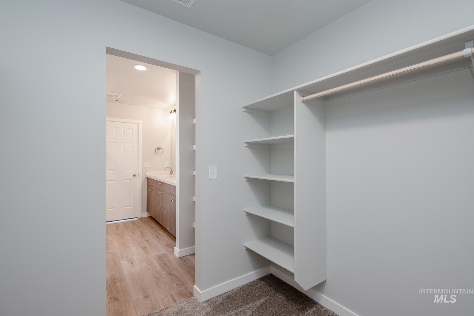 Walk in closet with light wood-style flooring
