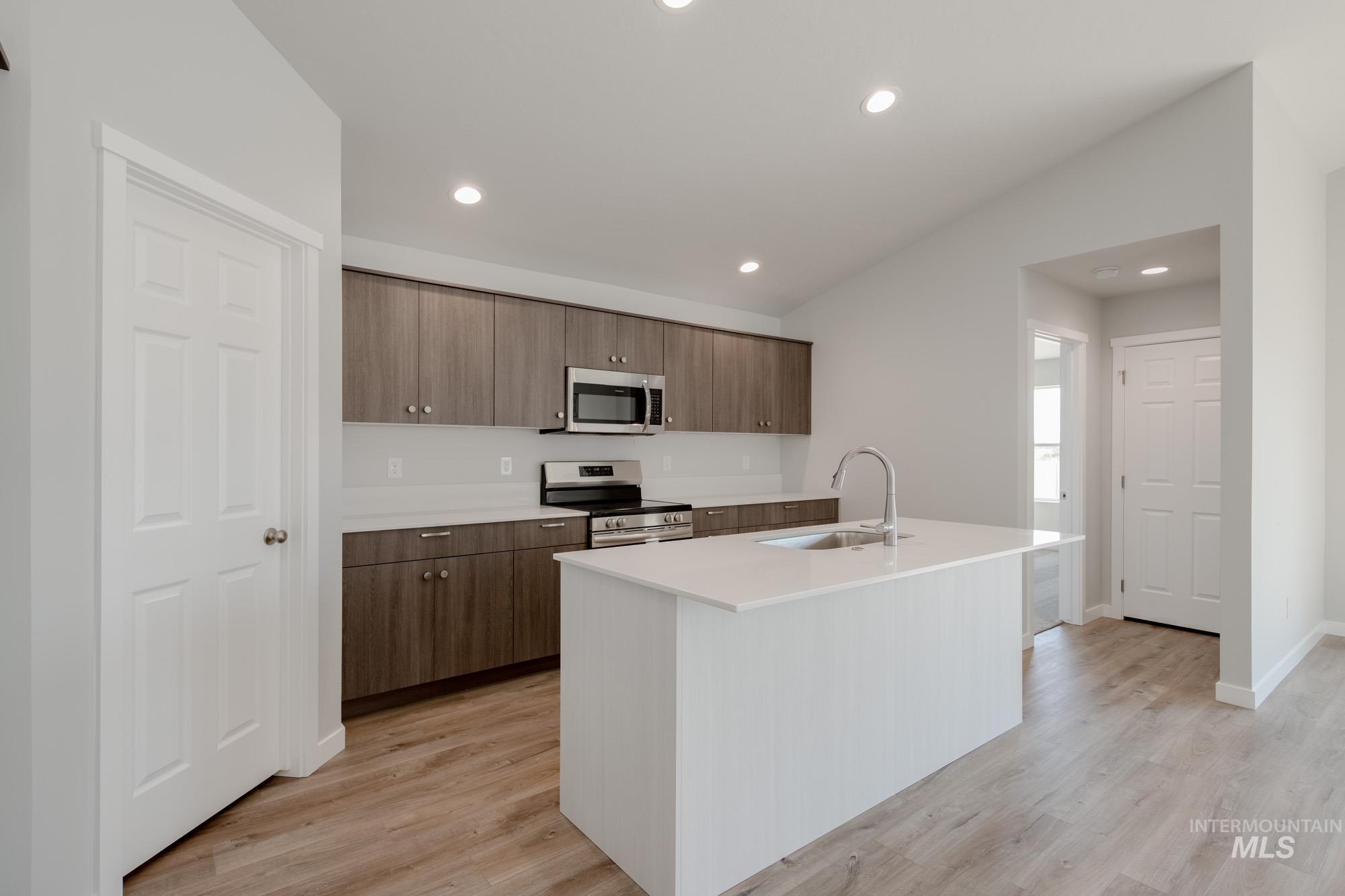 Kitchen with appliances with stainless steel finishes, recessed lighting, an island with sink, light wood-style flooring, and modern cabinets