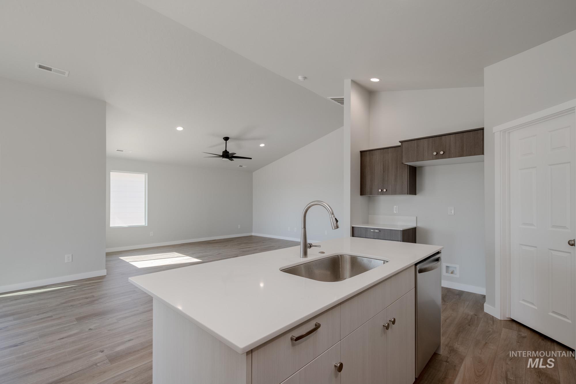 Kitchen with lofted ceiling, light wood-style flooring, an island with sink, modern cabinets, and ceiling fan