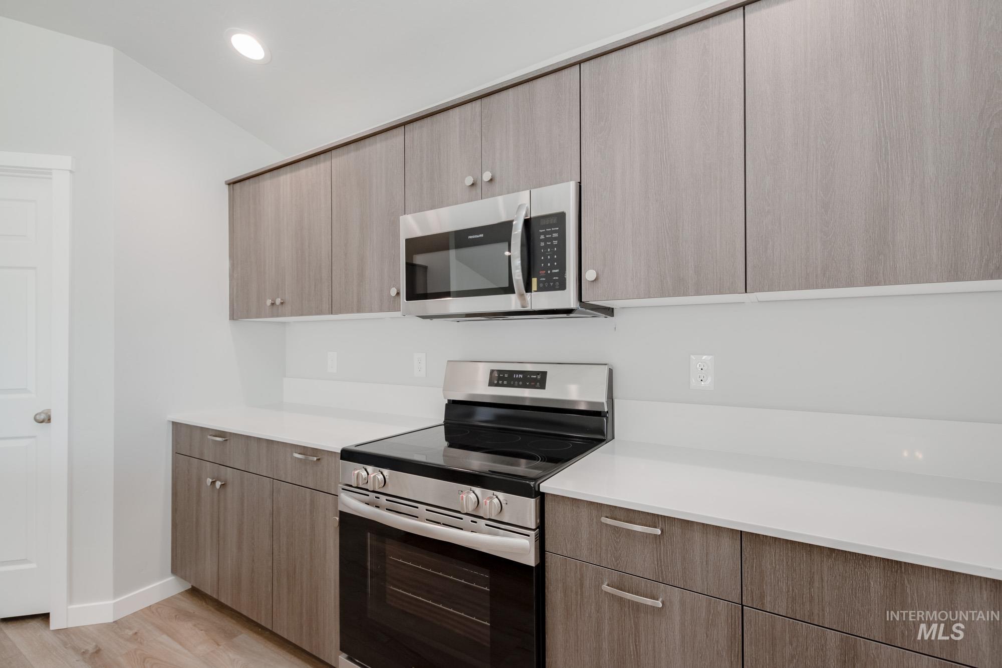 Kitchen with stainless steel appliances, light wood finished floors, modern cabinets, recessed lighting, and light stone counters