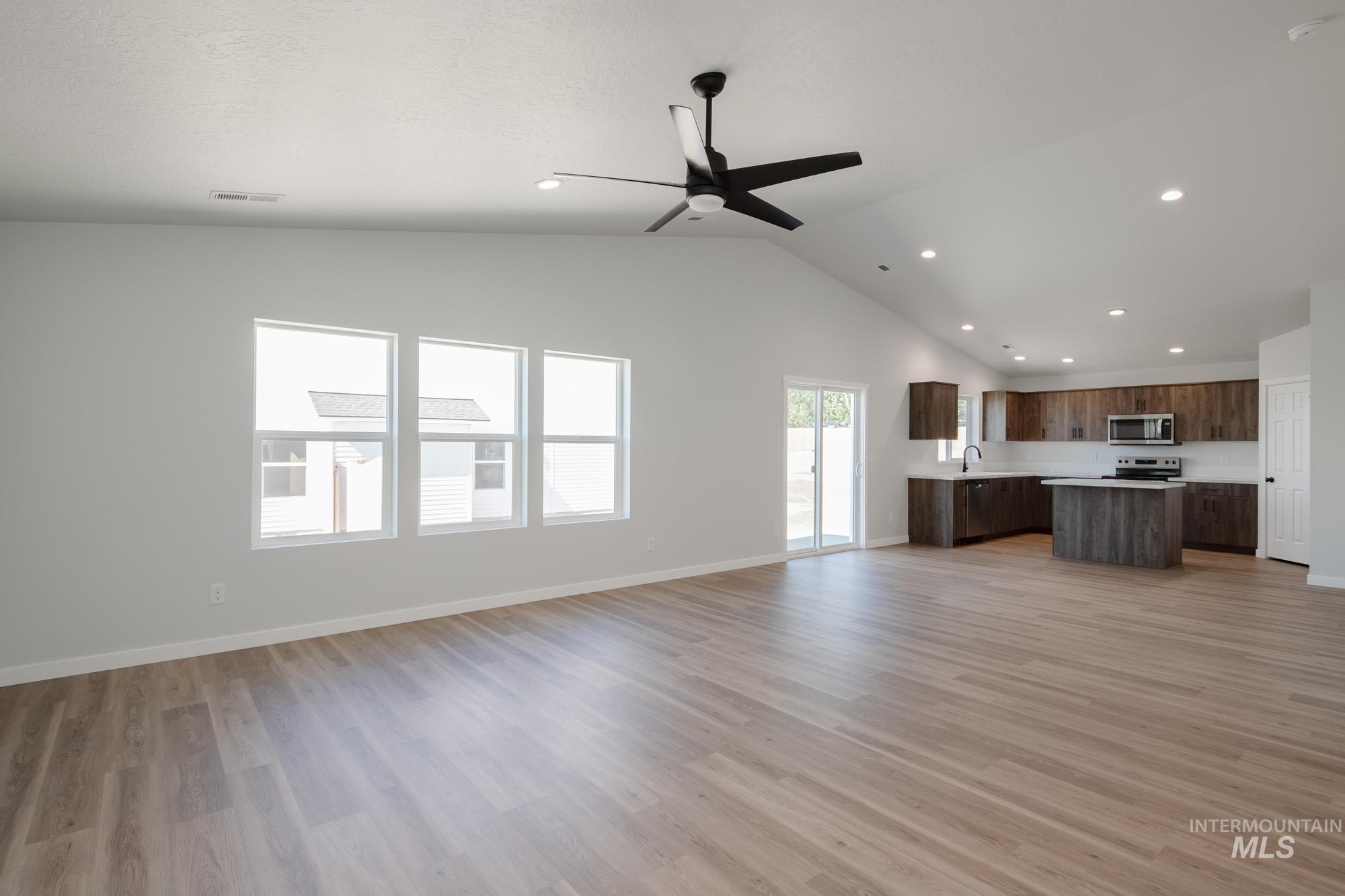 Unfurnished living room with light wood-style floors, a ceiling fan, recessed lighting, and high vaulted ceiling