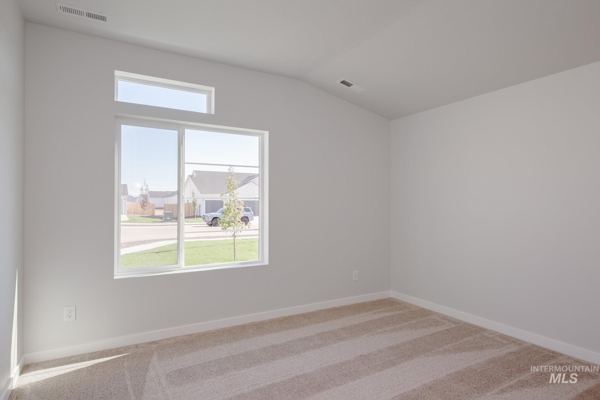 Carpeted empty room featuring baseboards and vaulted ceiling