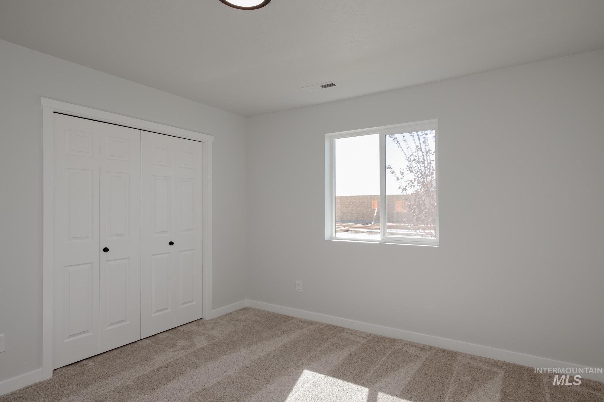 Unfurnished bedroom with light colored carpet and a closet