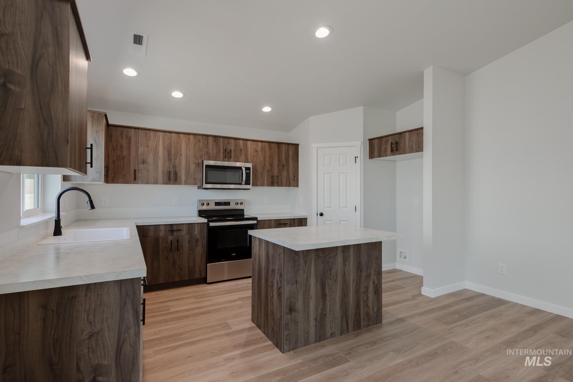 Kitchen with a kitchen island, appliances with stainless steel finishes, light countertops, recessed lighting, and light wood-style flooring