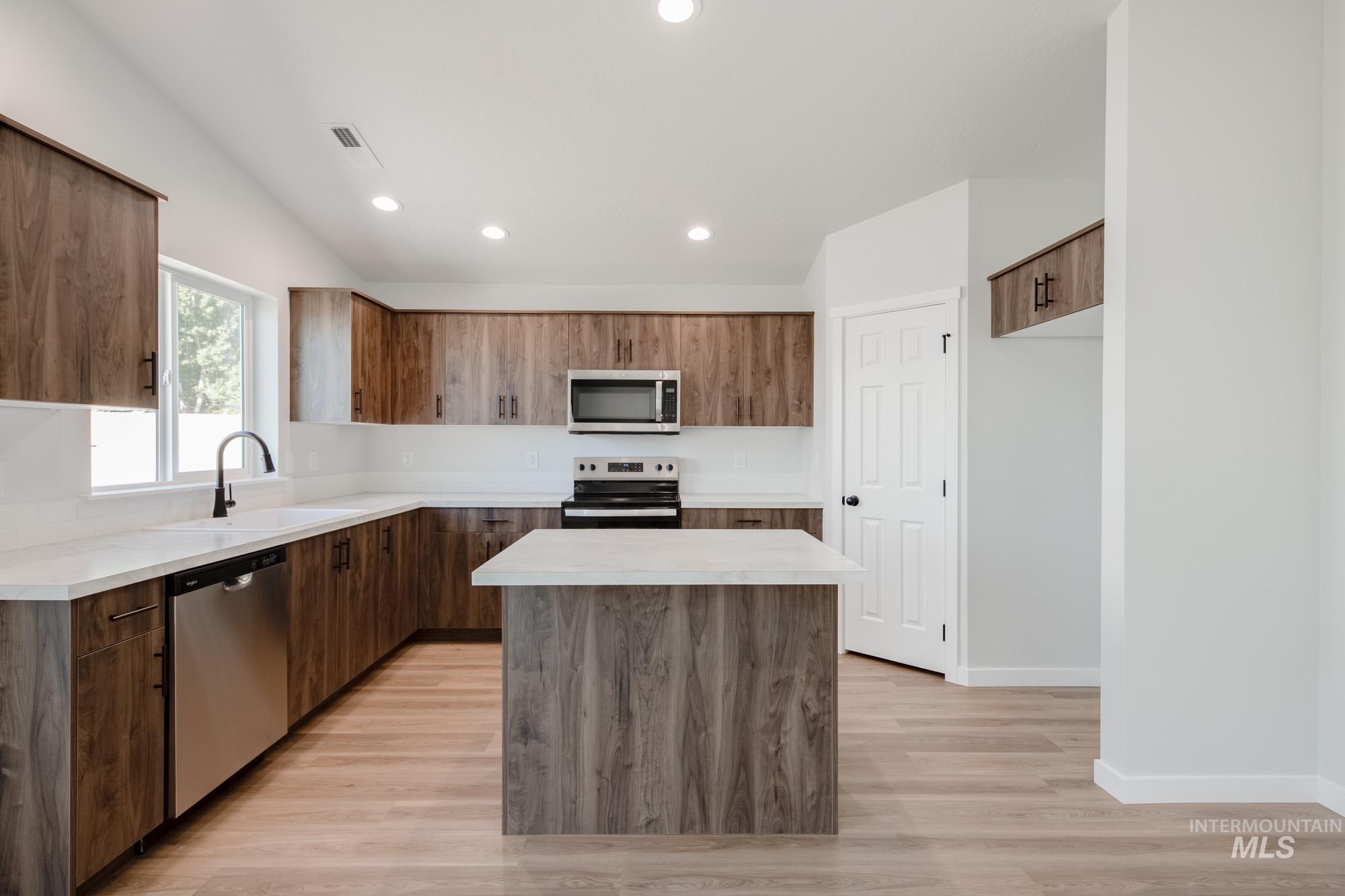Kitchen with a center island, light countertops, appliances with stainless steel finishes, recessed lighting, and light wood finished floors