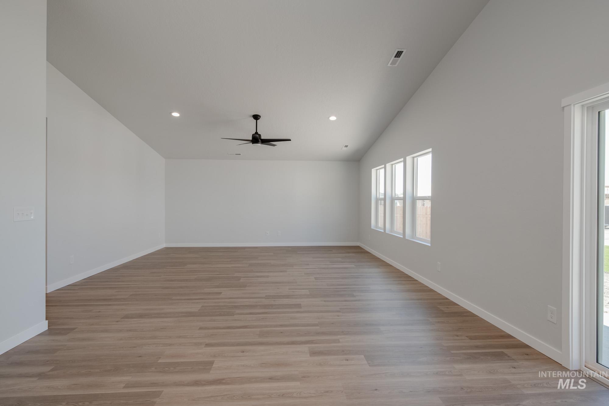 Empty room featuring light wood finished floors, vaulted ceiling, recessed lighting, and ceiling fan