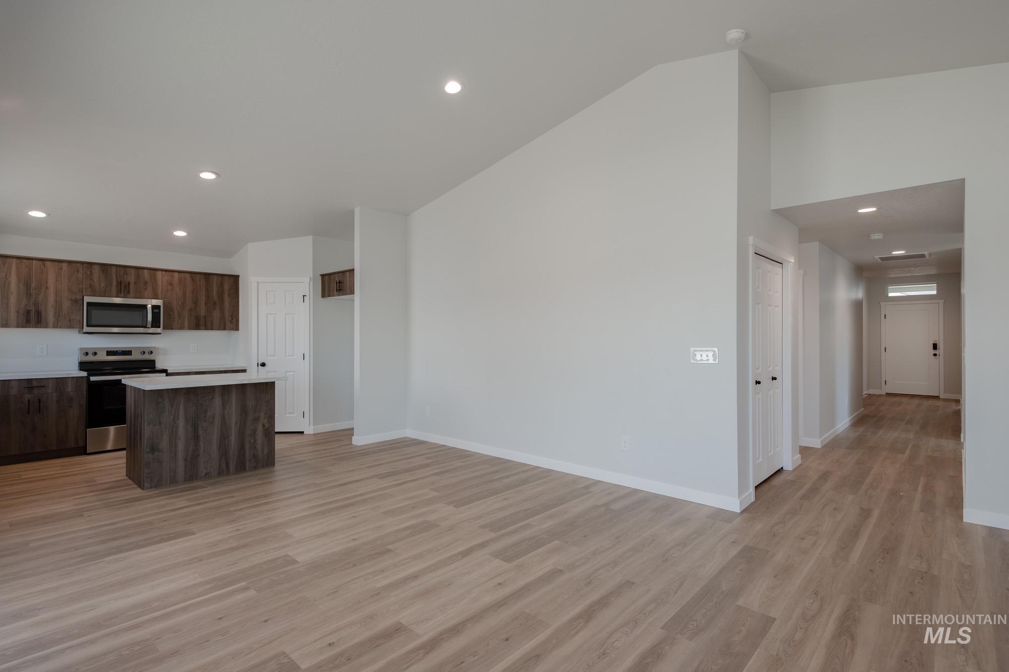 Kitchen with recessed lighting, a kitchen island, light countertops, appliances with stainless steel finishes, and light wood finished floors