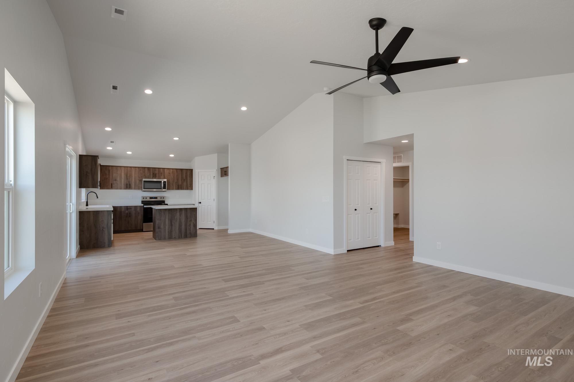 Unfurnished living room featuring light wood-style flooring, recessed lighting, high vaulted ceiling, and ceiling fan