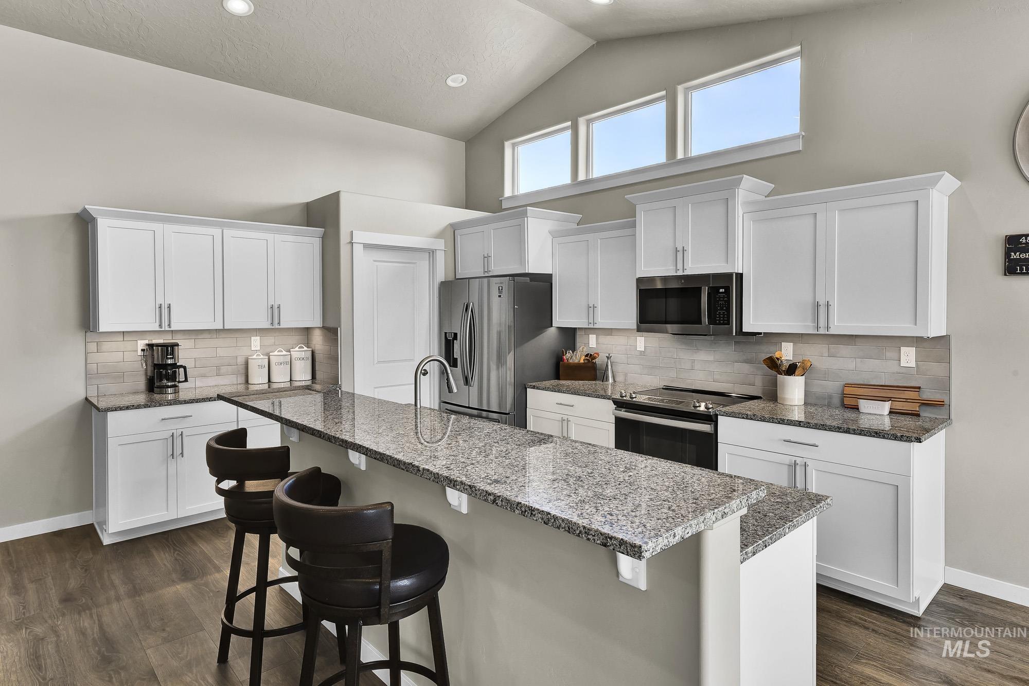 Kitchen featuring white cabinetry, high vaulted ceiling, backsplash, appliances with stainless steel finishes, and recessed lighting