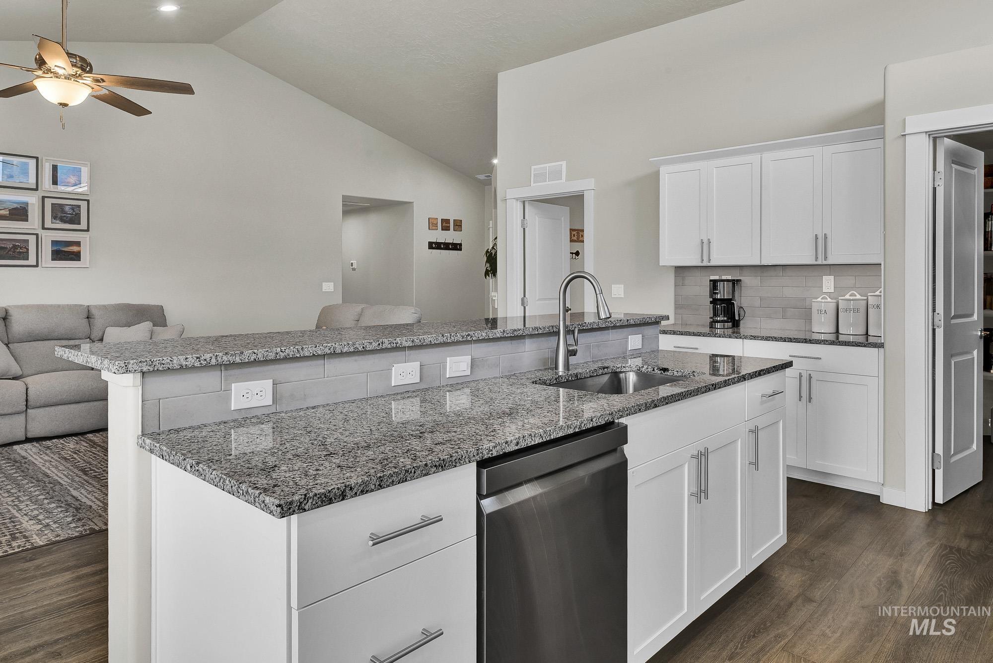 Kitchen featuring white cabinets, open floor plan, dark stone countertops, tasteful backsplash, and dark wood-style floors