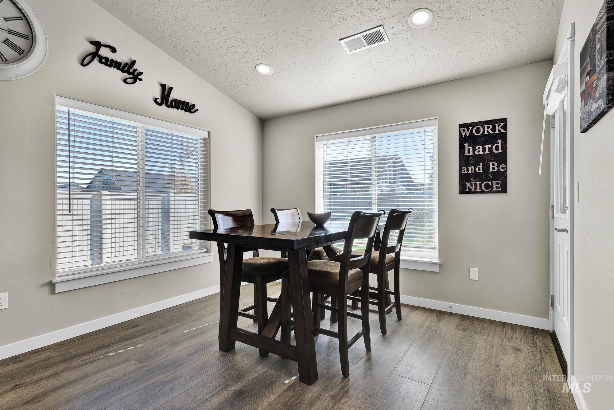Dining room with lofted ceiling, recessed lighting, dark wood-style flooring, and a textured ceiling