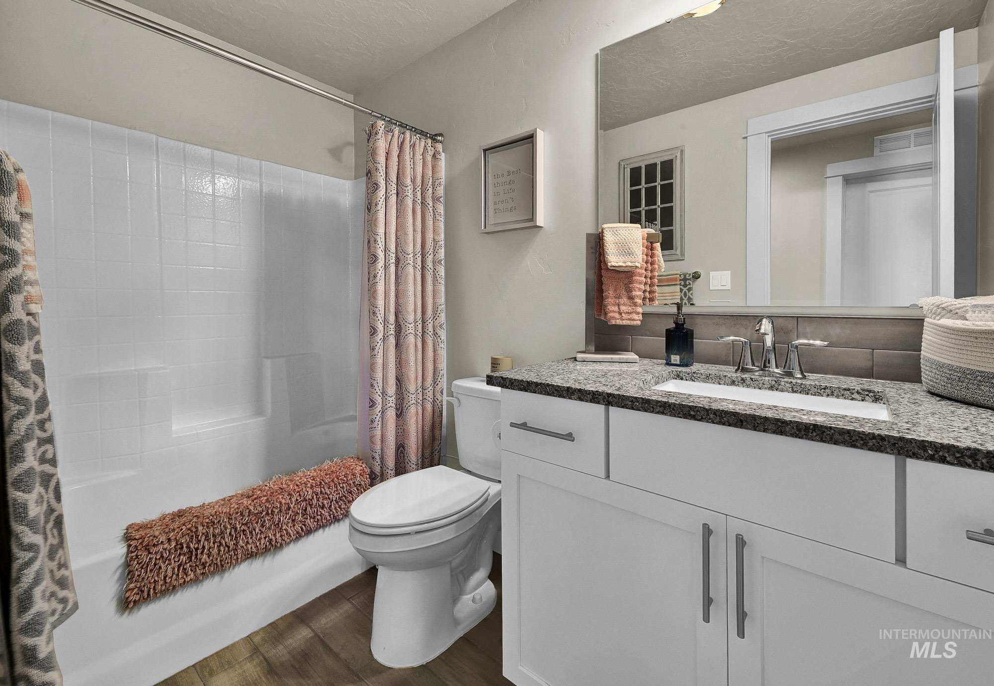 Bathroom with vanity, dark wood-style flooring, a textured ceiling, and shower / bathtub combination with curtain