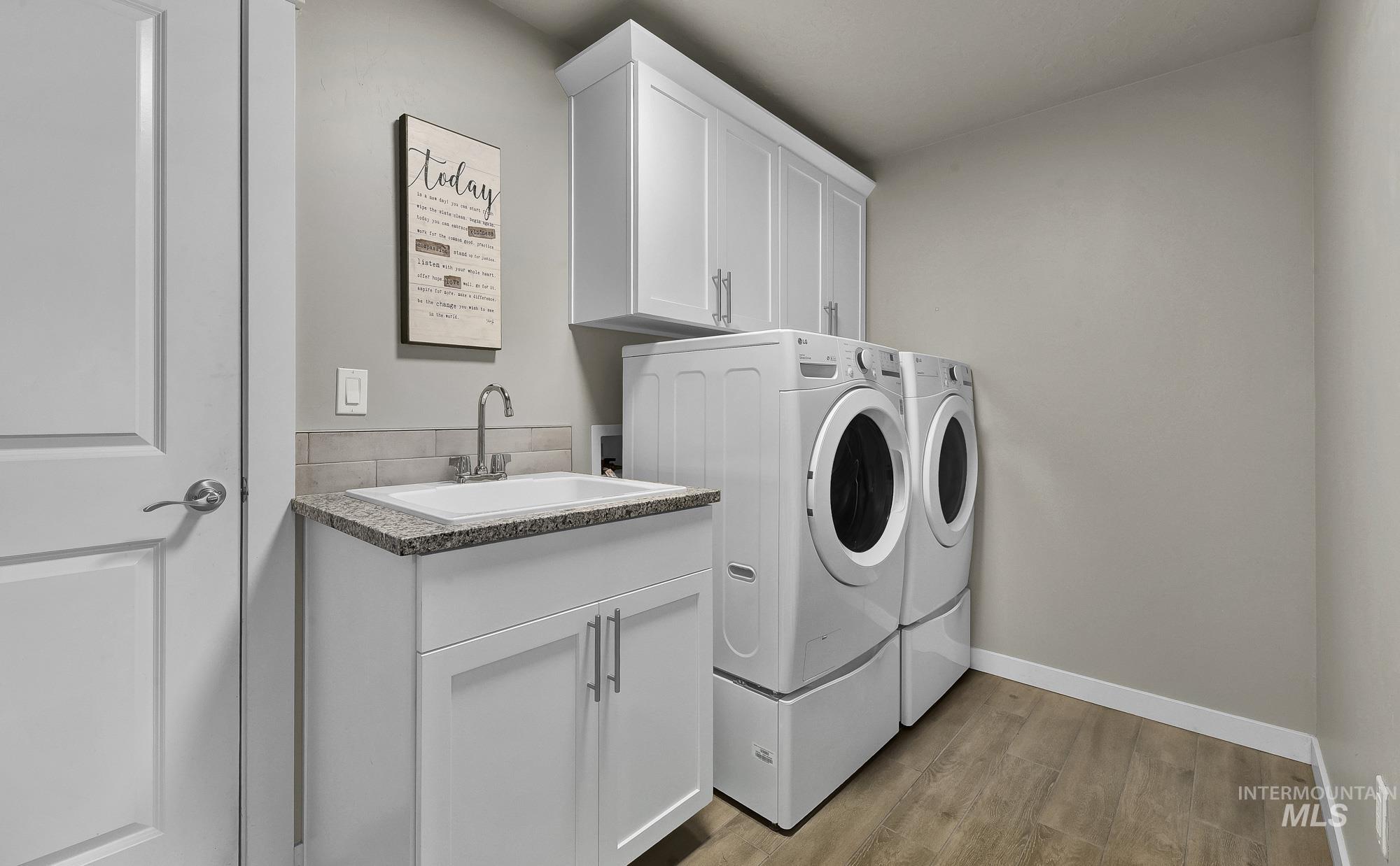 Washroom with cabinet space, light wood-style flooring, and independent washer and dryer