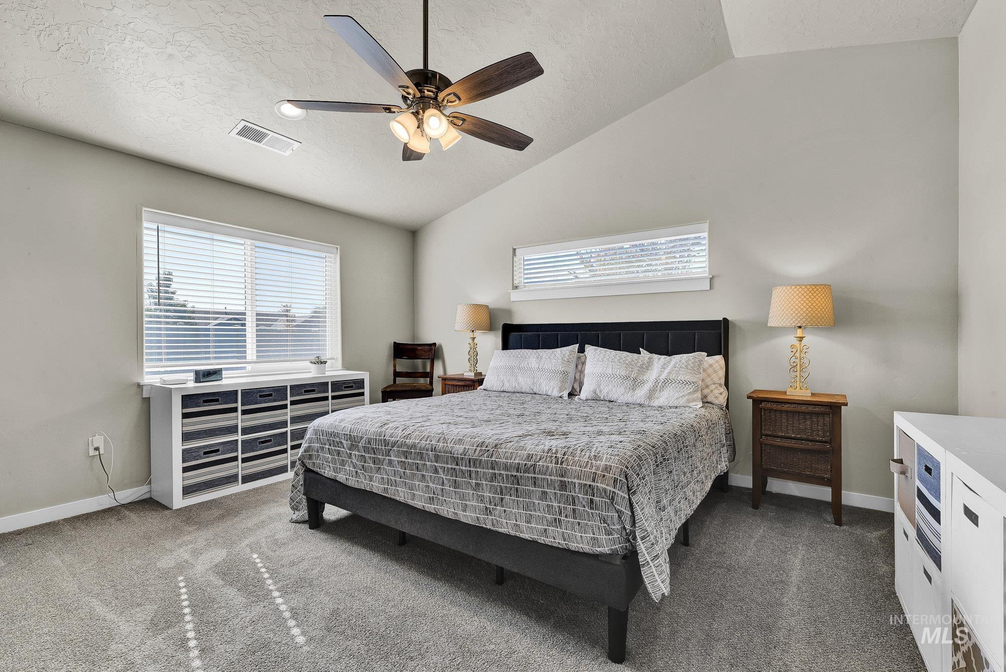 Bedroom featuring carpet, a textured ceiling, lofted ceiling, and ceiling fan