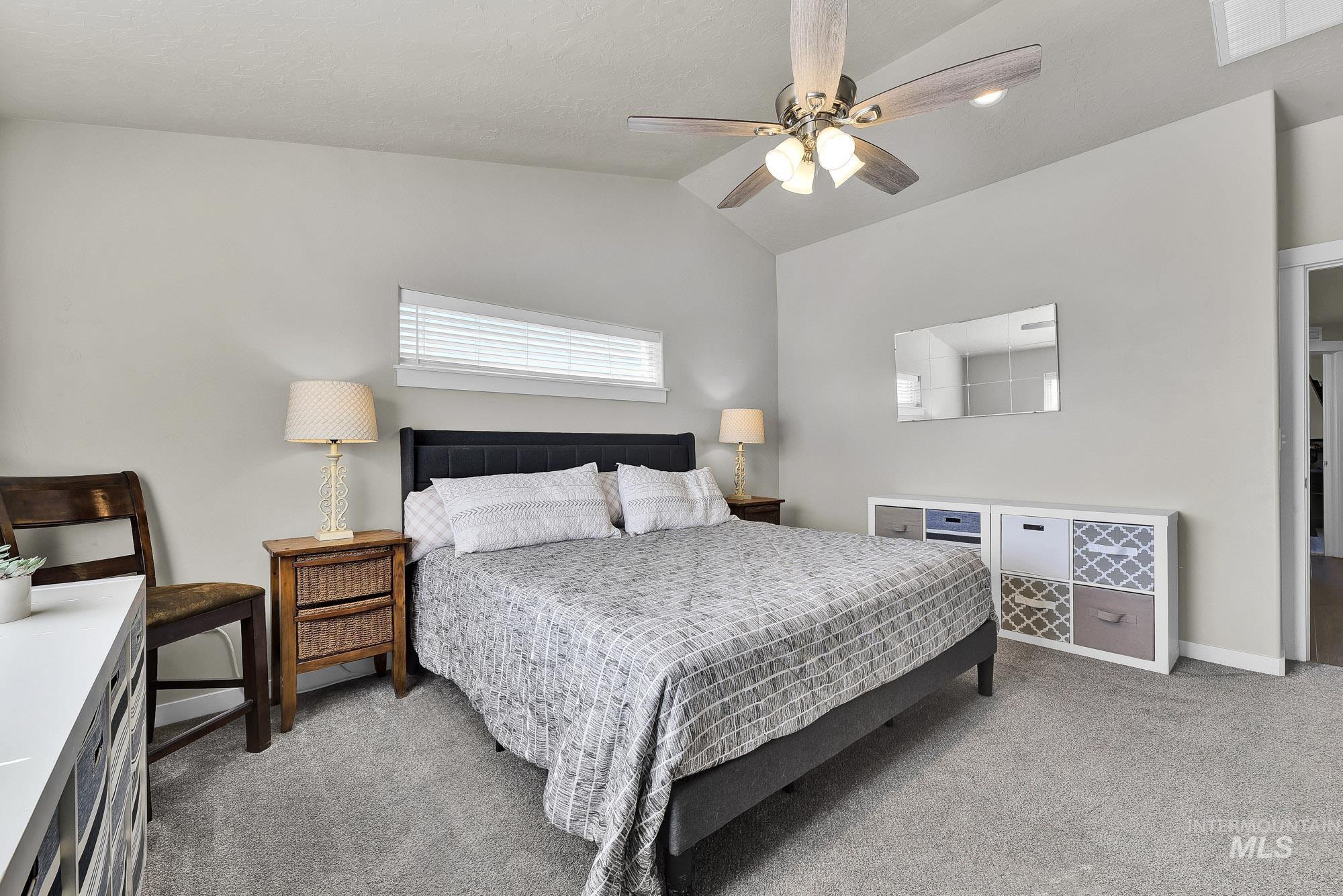 Bedroom with vaulted ceiling, light carpet, and a ceiling fan