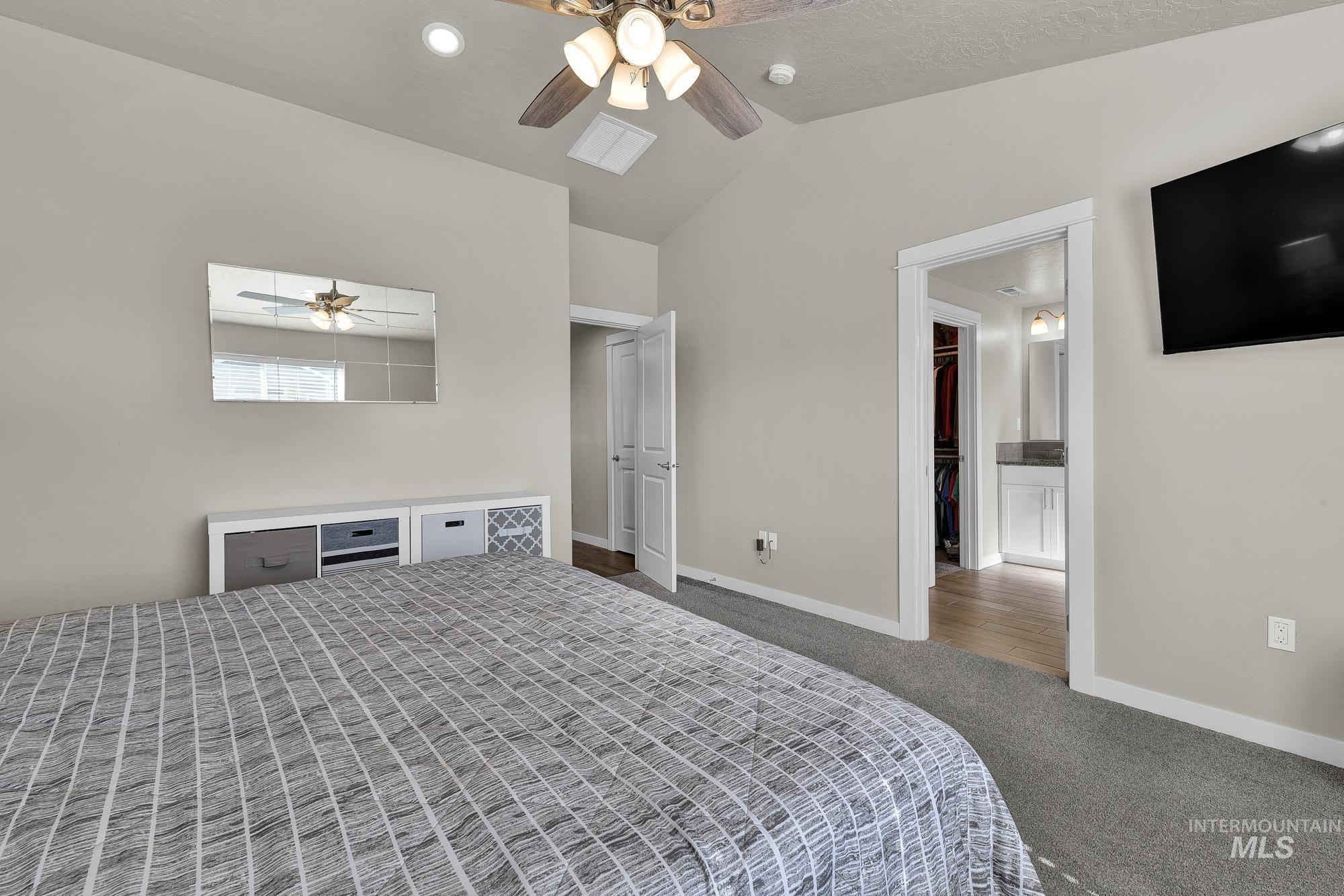 Bedroom with dark colored carpet, vaulted ceiling, ceiling fan, and recessed lighting
