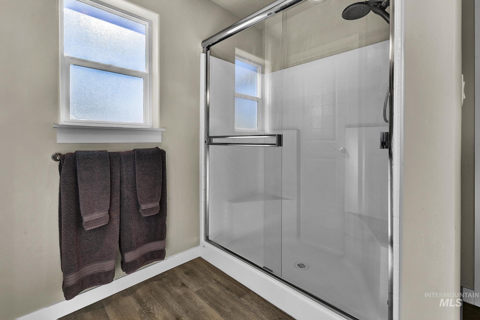 Bathroom with dark wood-style flooring and a shower stall