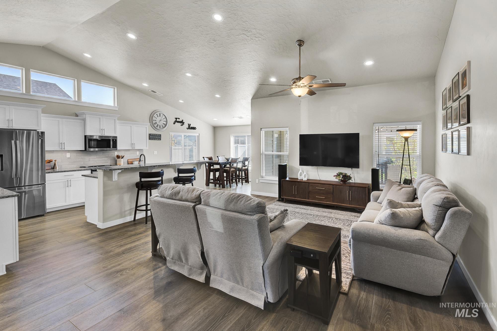 Living area with recessed lighting, a textured ceiling, dark wood finished floors, high vaulted ceiling, and ceiling fan