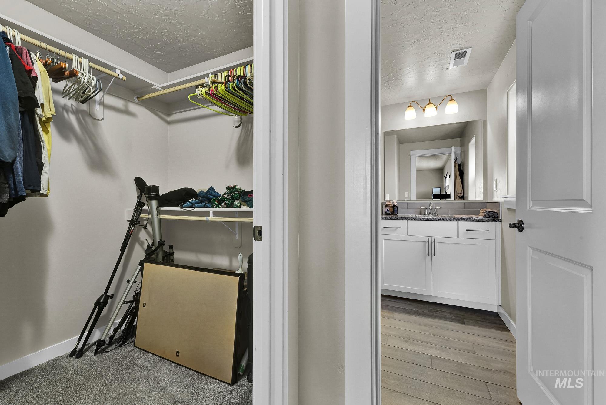 Bathroom featuring vanity, a textured ceiling, light wood-style flooring, and a spacious closet