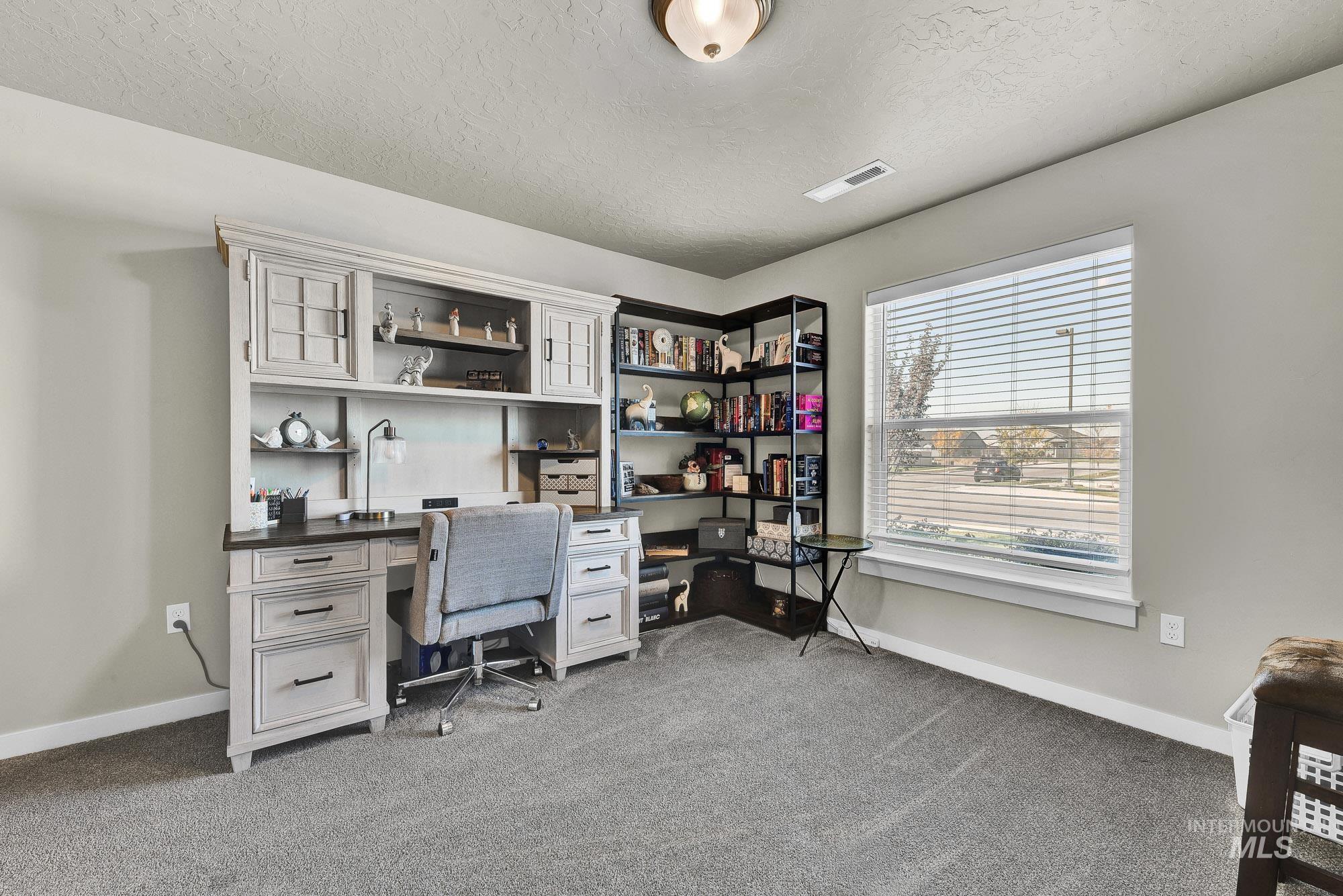 Office area featuring dark carpet and a textured ceiling