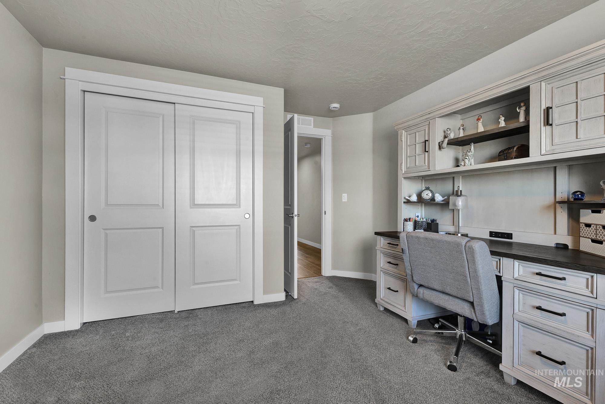 Office space with dark carpet and a textured ceiling
