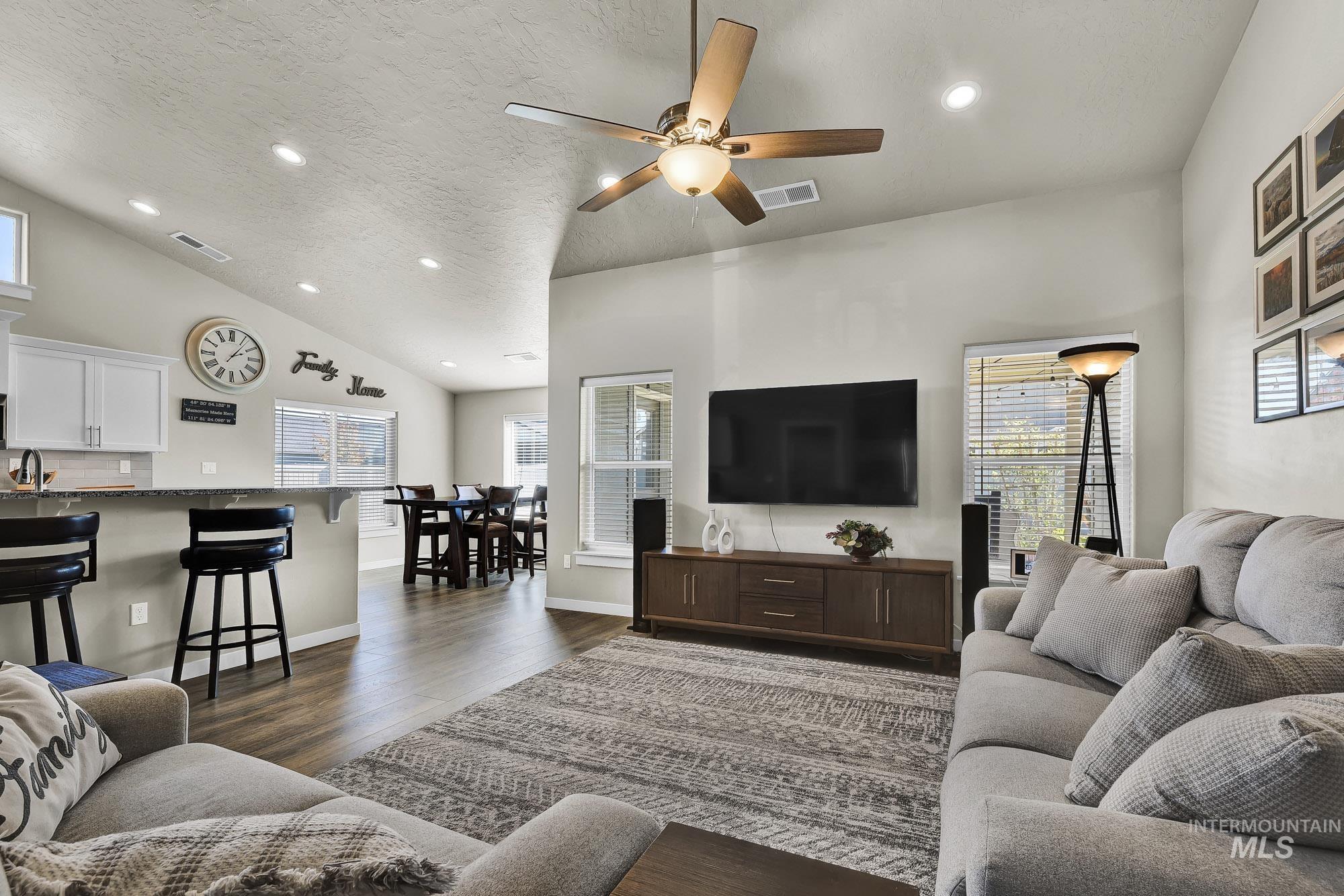 Living area featuring recessed lighting, dark wood finished floors, a ceiling fan, a textured ceiling, and lofted ceiling