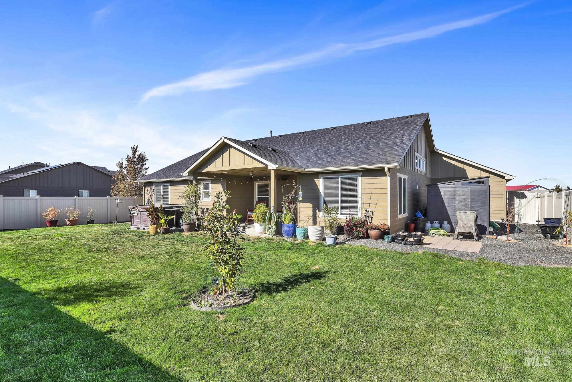 Back of house featuring a patio, a fenced backyard, a shingled roof, and board and batten siding
