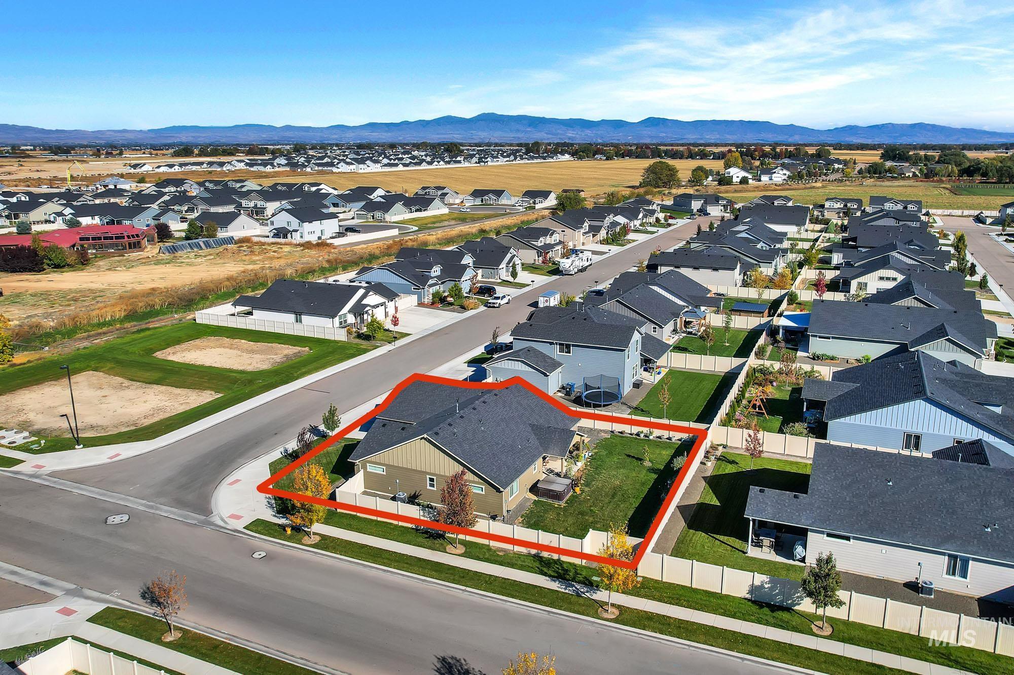 Aerial perspective of suburban area featuring property boundaries highlighted and a mountainous background