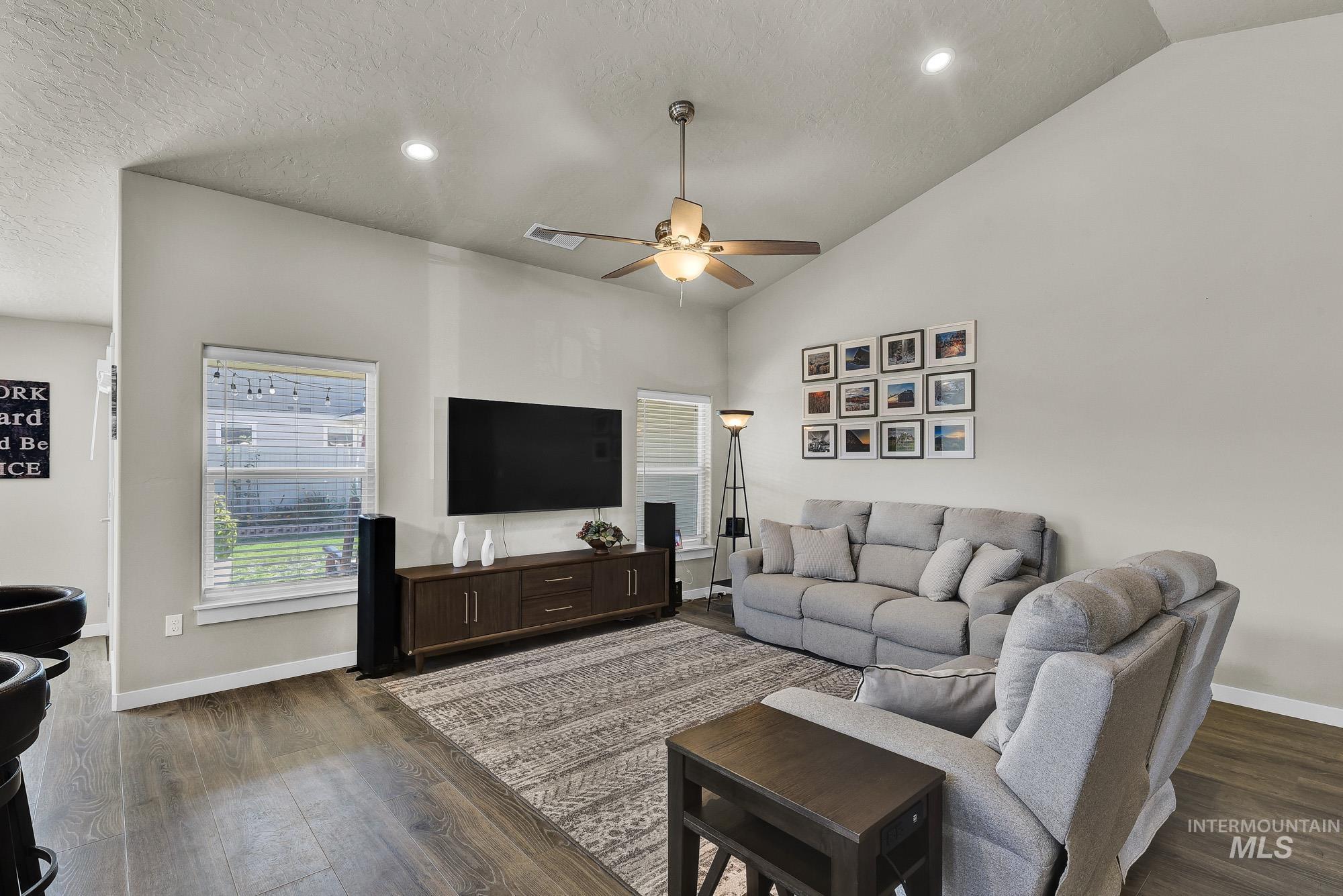 Living room with a textured ceiling, vaulted ceiling, a ceiling fan, dark wood finished floors, and recessed lighting