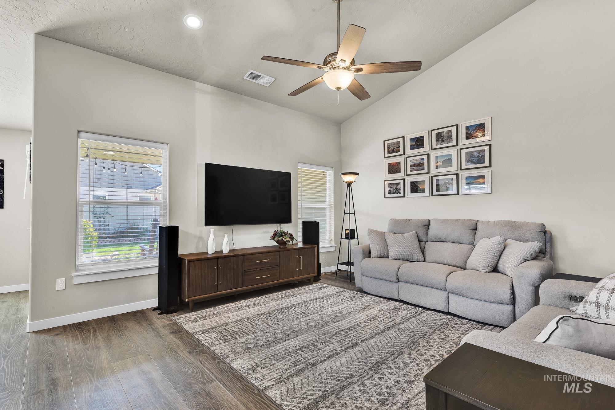 Living room with lofted ceiling, a ceiling fan, wood finished floors, a textured ceiling, and recessed lighting