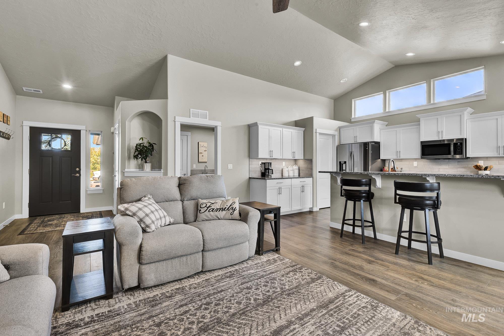 Living room featuring a textured ceiling, high vaulted ceiling, dark wood-style floors, and recessed lighting