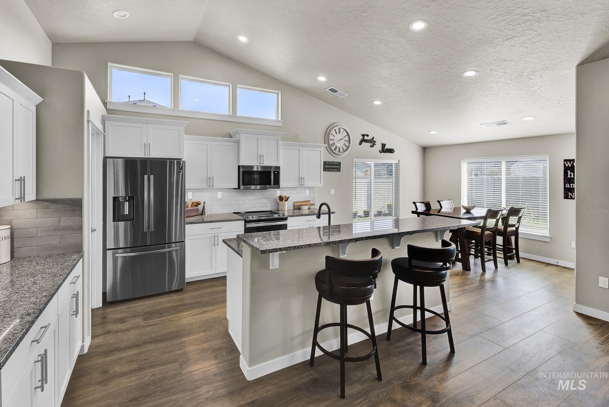 Kitchen with appliances with stainless steel finishes, a textured ceiling, backsplash, recessed lighting, and white cabinets