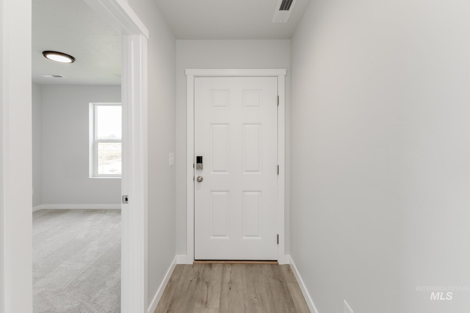 Doorway featuring baseboards and wood finished floors