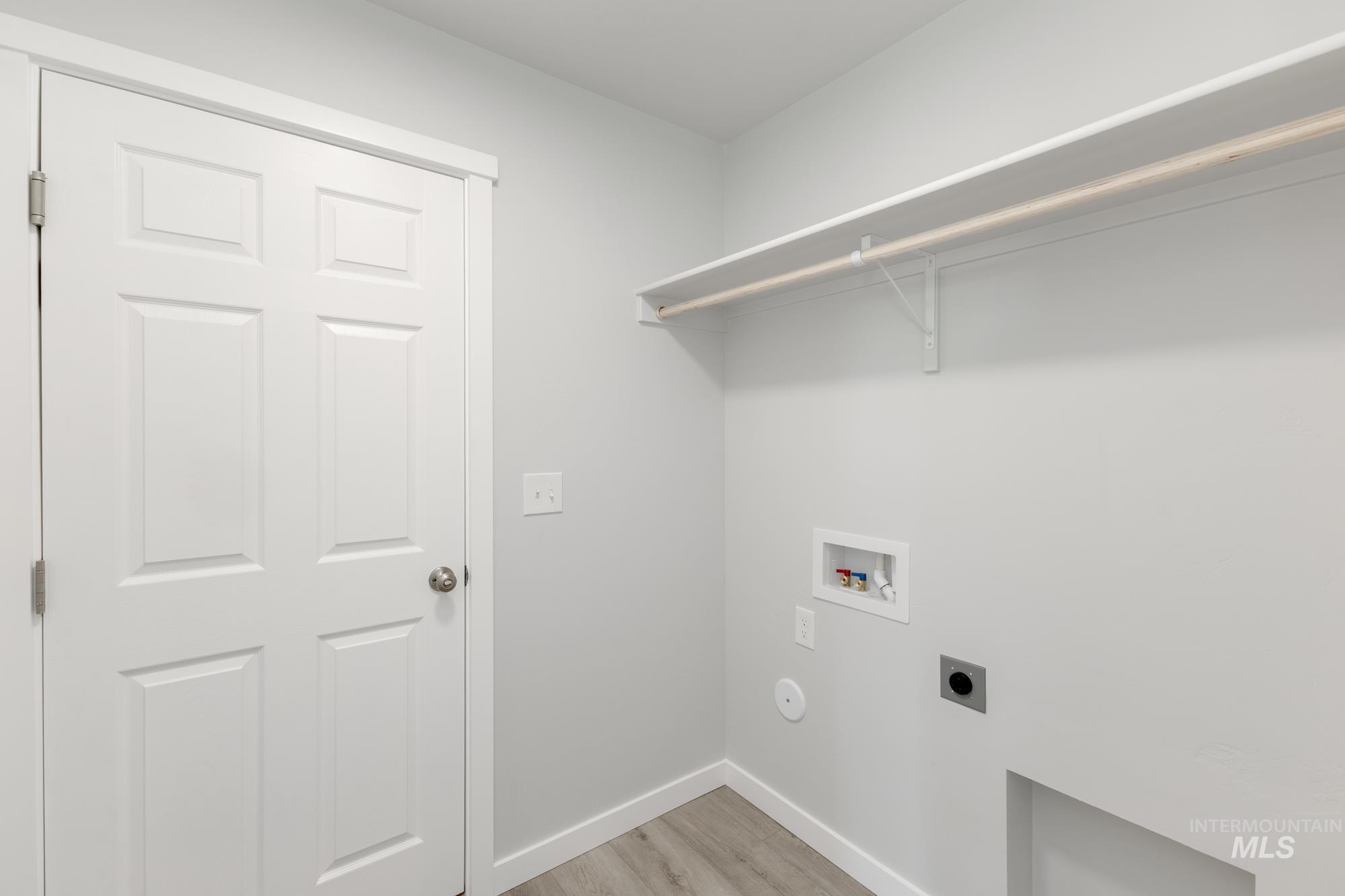 Laundry area with light wood-style floors, hookup for an electric dryer, and washer hookup