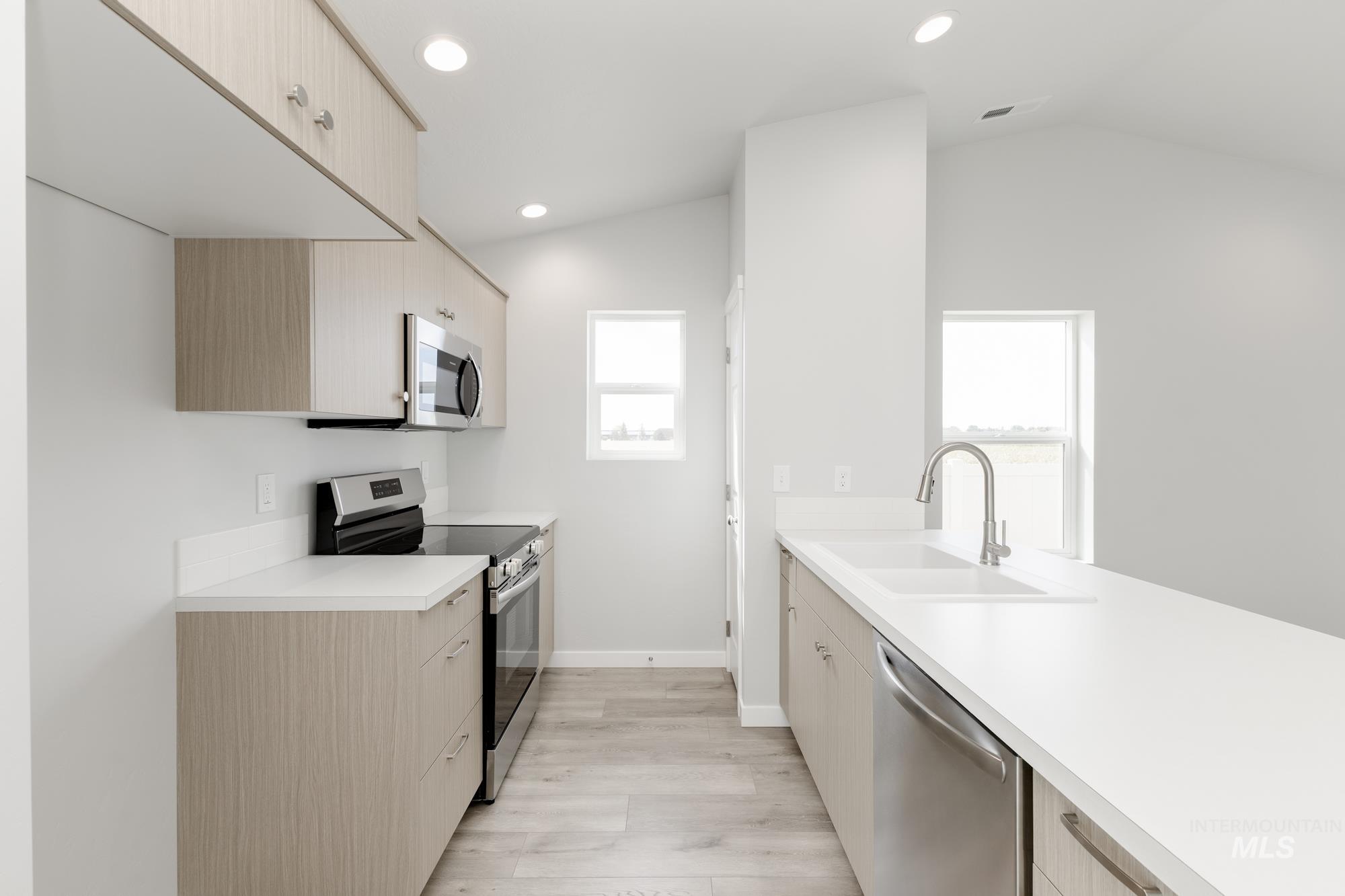 Kitchen featuring stainless steel appliances, light countertops, light wood-style flooring, light brown cabinetry, and recessed lighting
