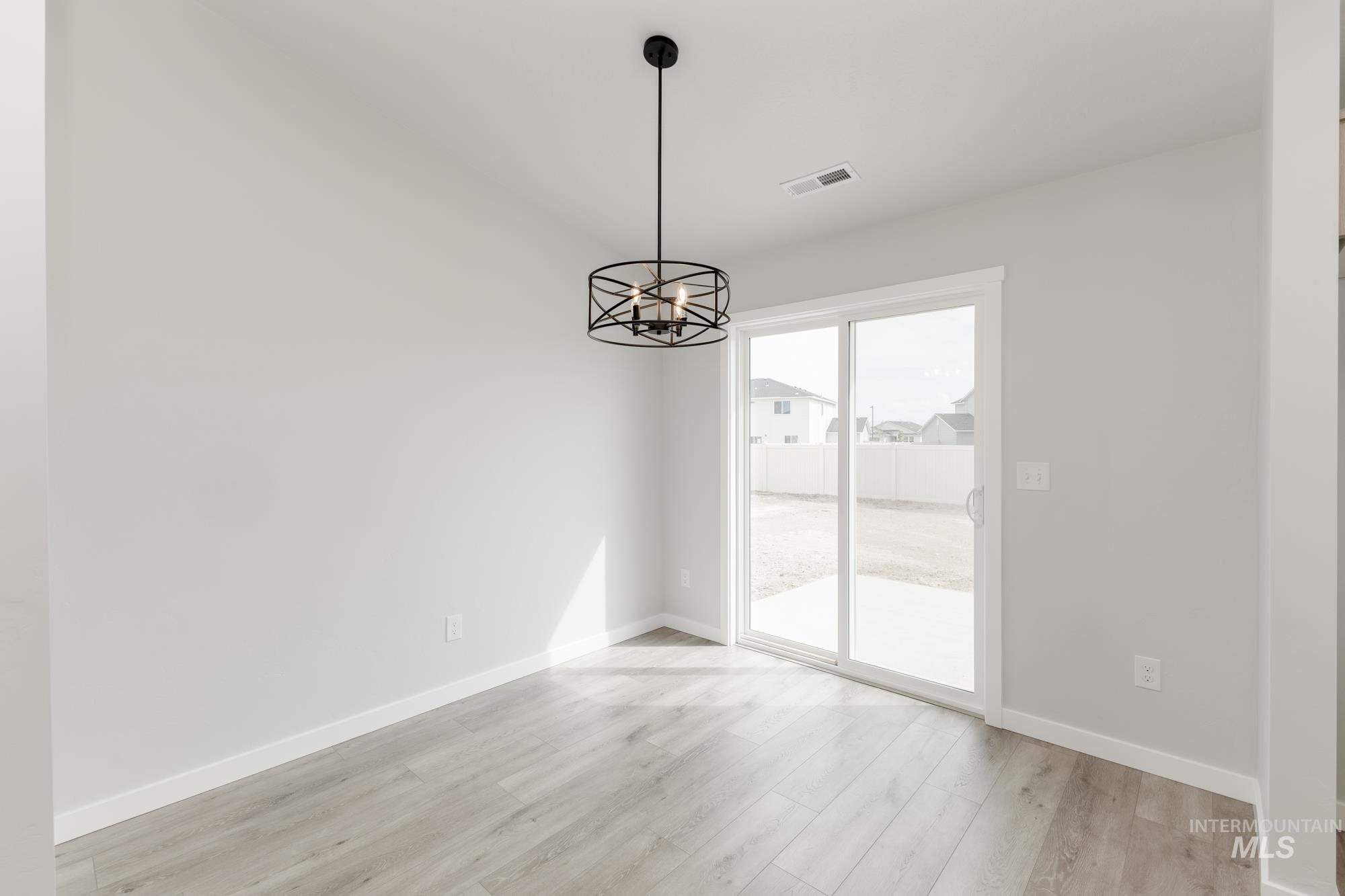 Unfurnished dining area with light wood-type flooring and a chandelier