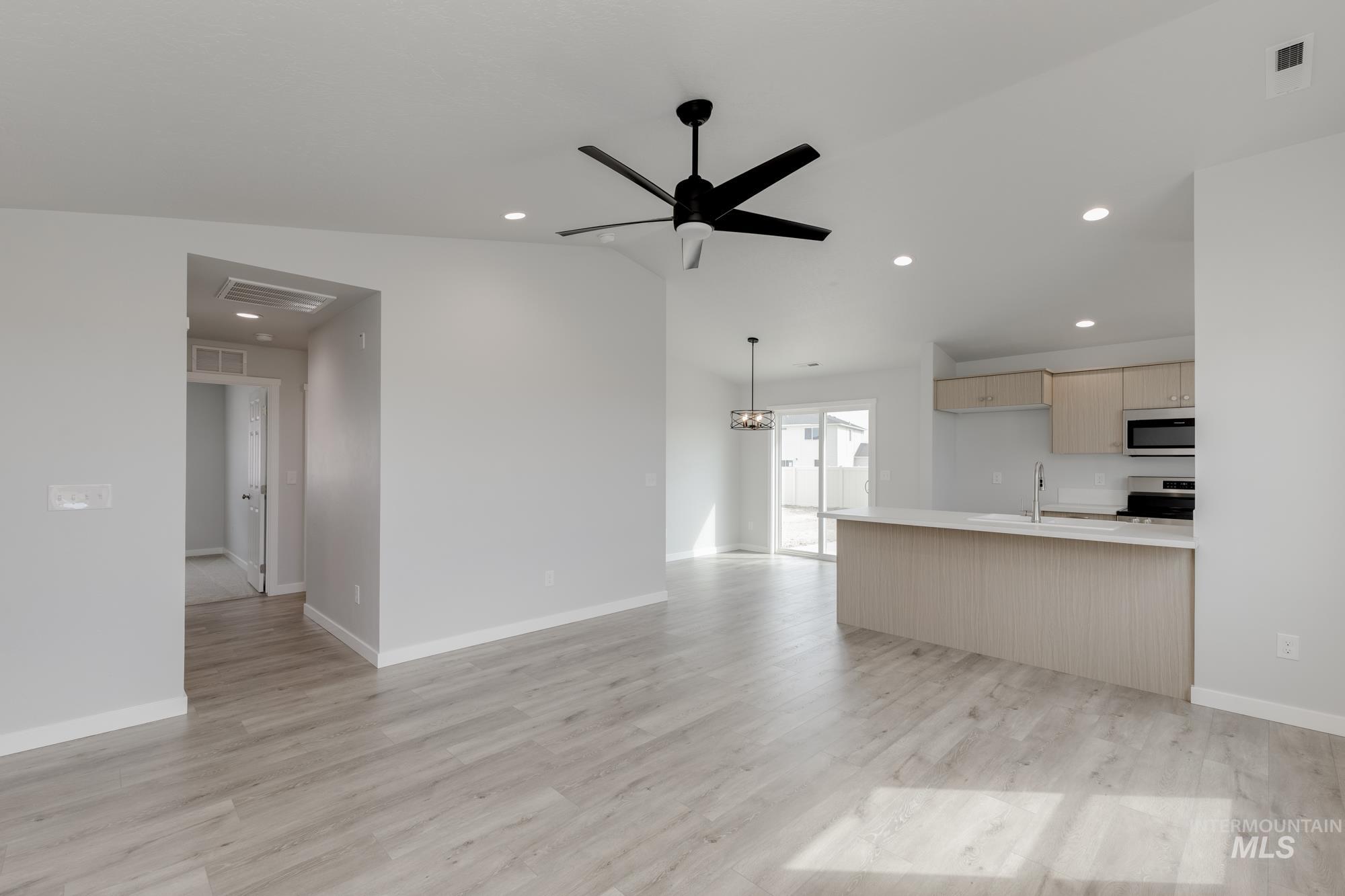 Unfurnished living room featuring recessed lighting, light wood-style floors, ceiling fan, lofted ceiling, and a chandelier