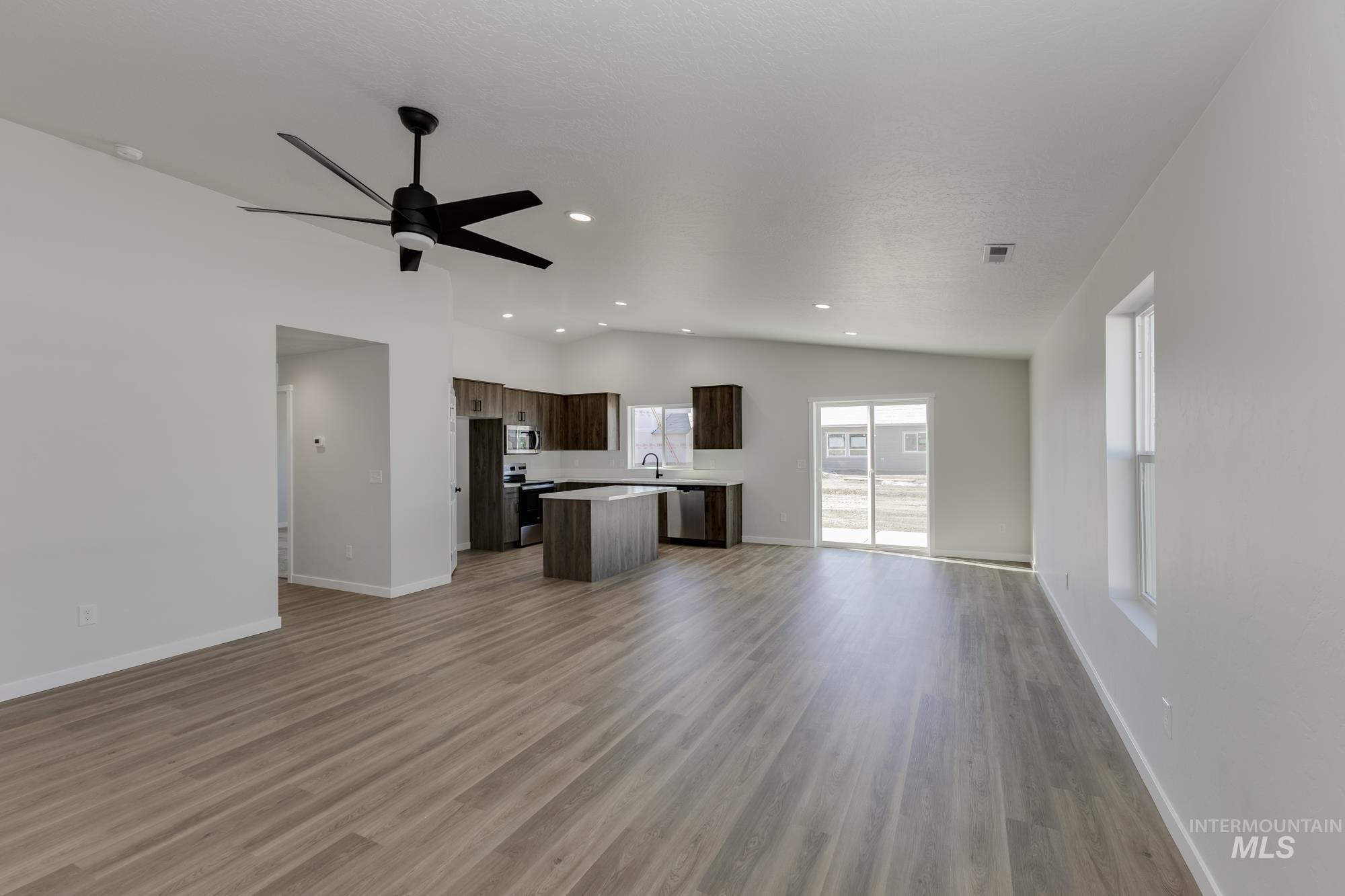 Unfurnished living room with light wood-style flooring, lofted ceiling, a ceiling fan, and recessed lighting