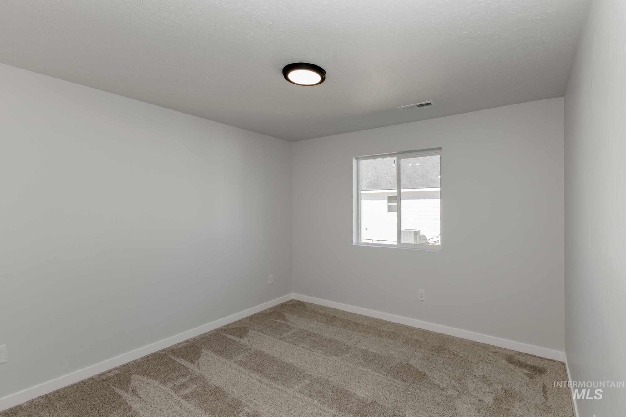 Carpeted spare room featuring baseboards