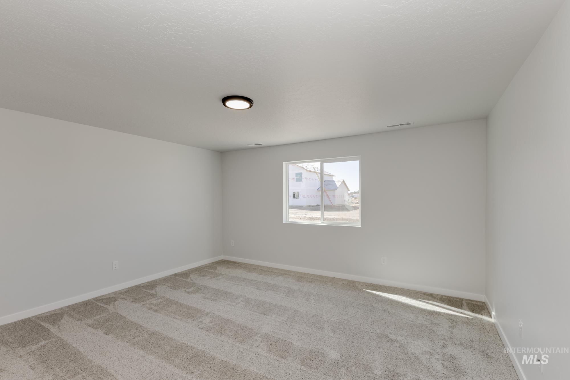Carpeted spare room featuring baseboards