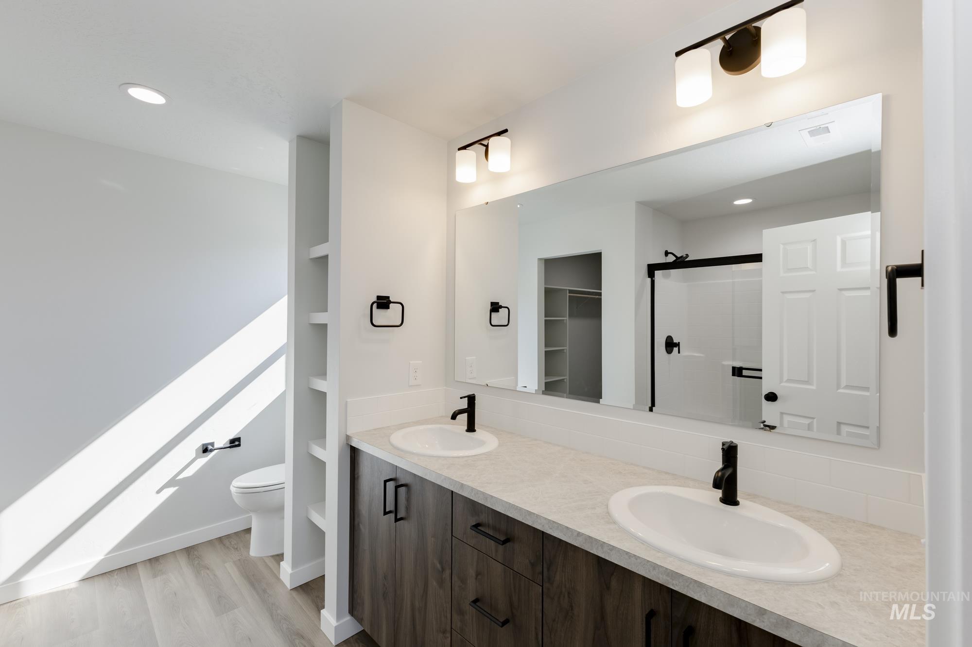 Bathroom with a shower stall, recessed lighting, double vanity, light wood-style flooring, and a spacious closet