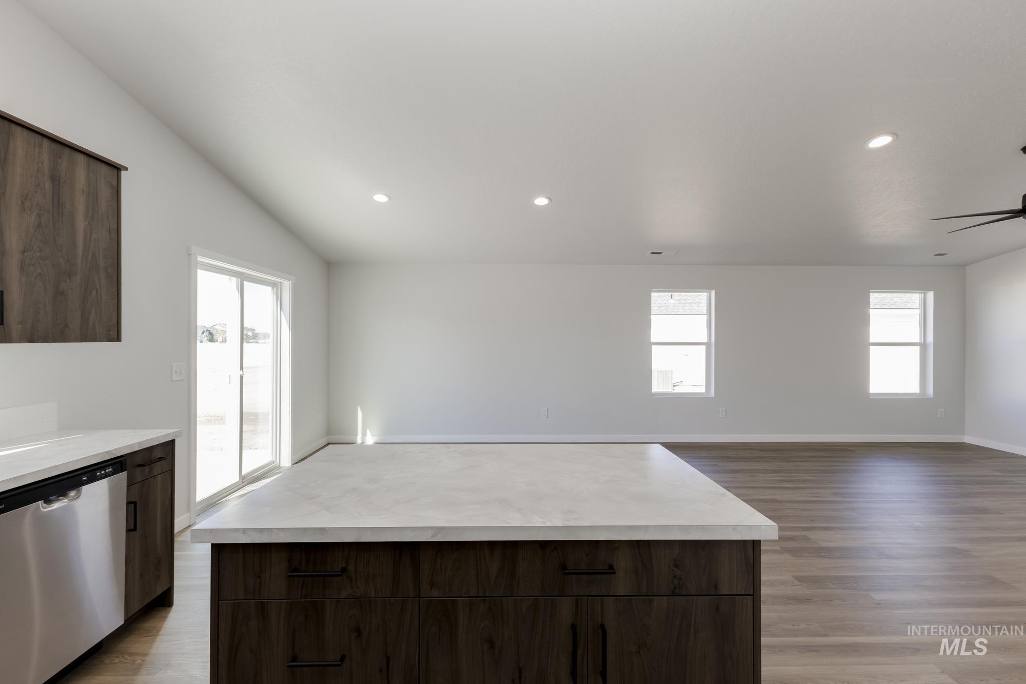 Kitchen with light countertops, stainless steel dishwasher, dark brown cabinets, and recessed lighting