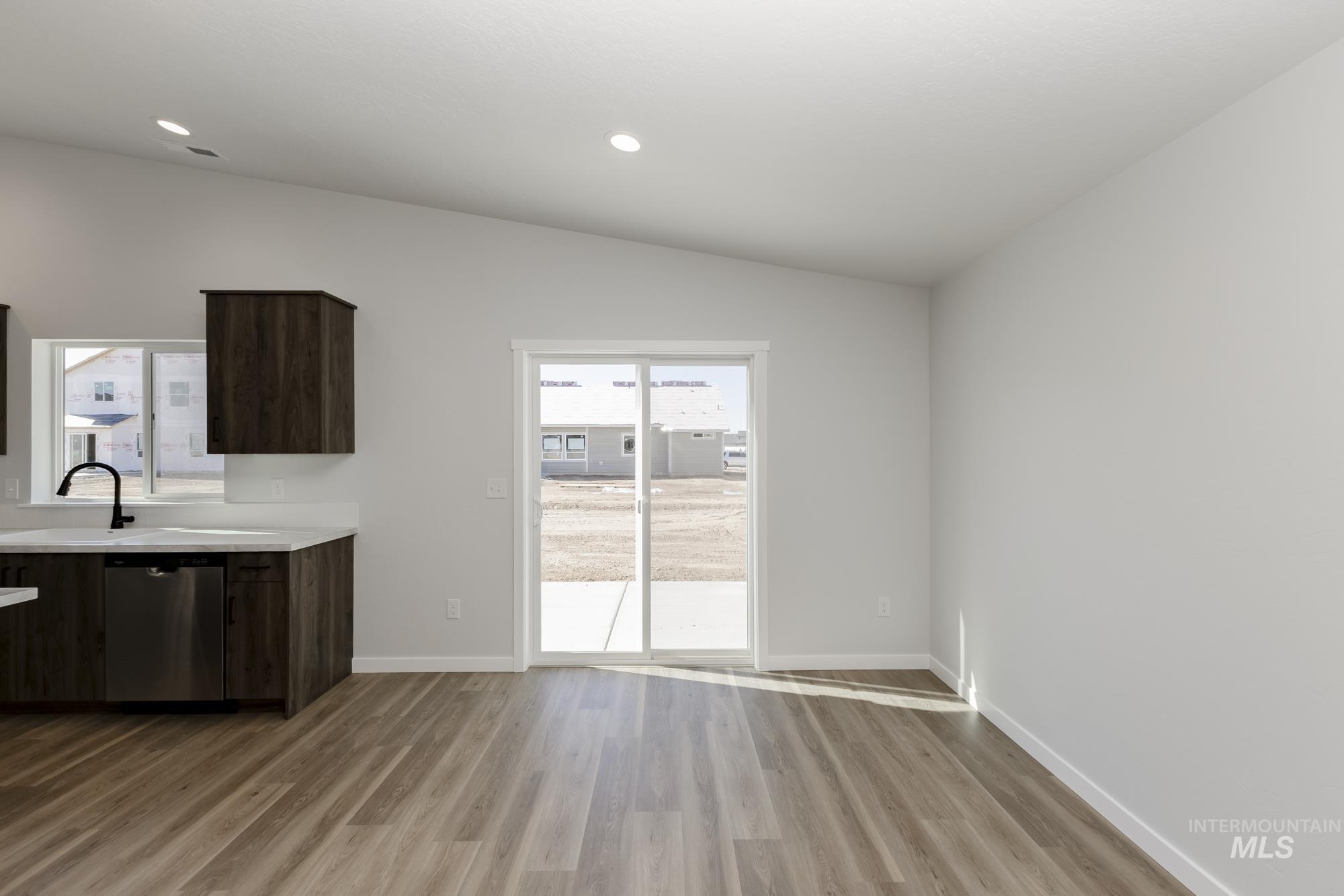 Kitchen with vaulted ceiling, stainless steel dishwasher, light wood-style flooring, recessed lighting, and dark brown cabinets