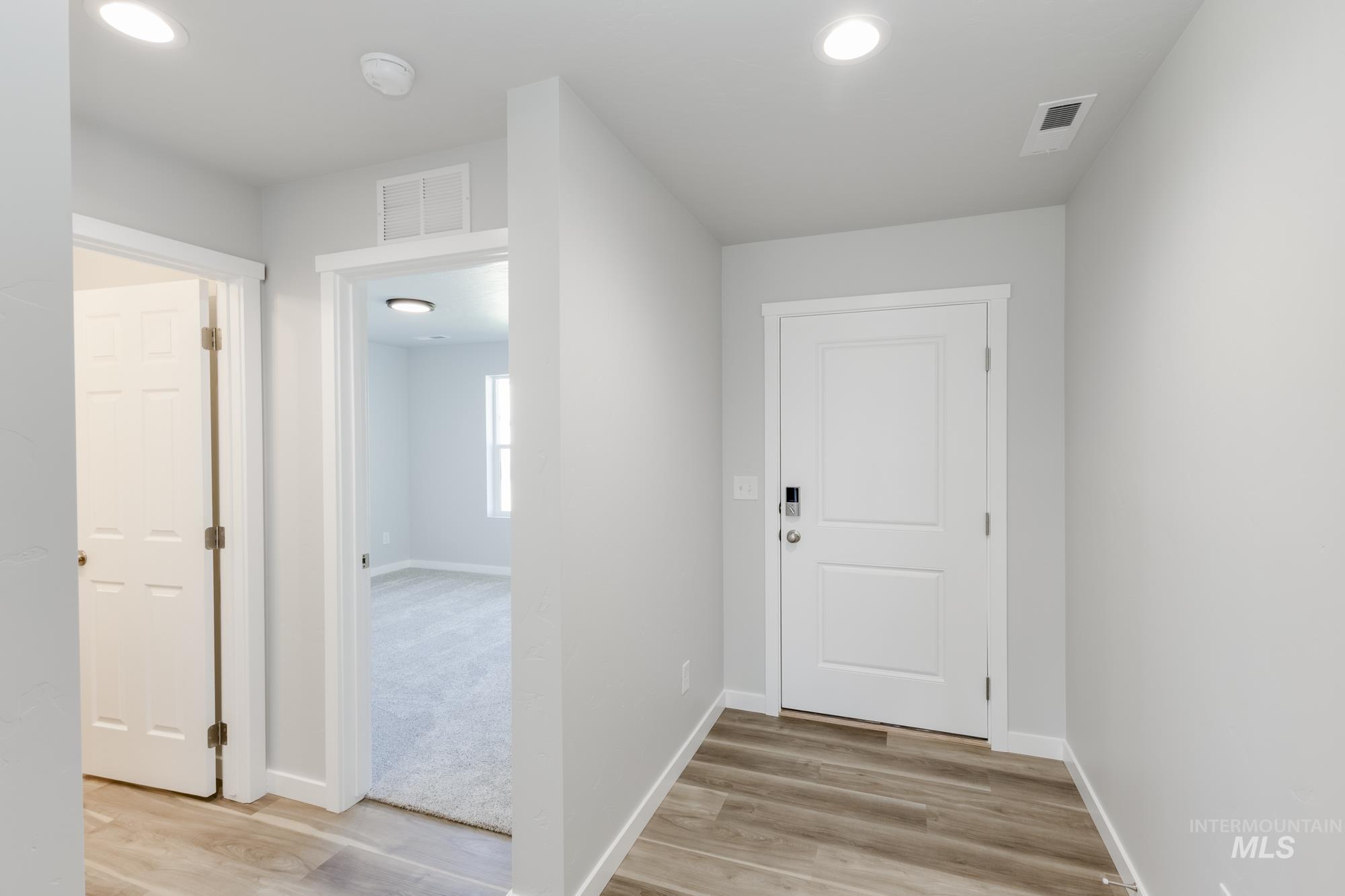 Hall with light wood-style floors and recessed lighting
