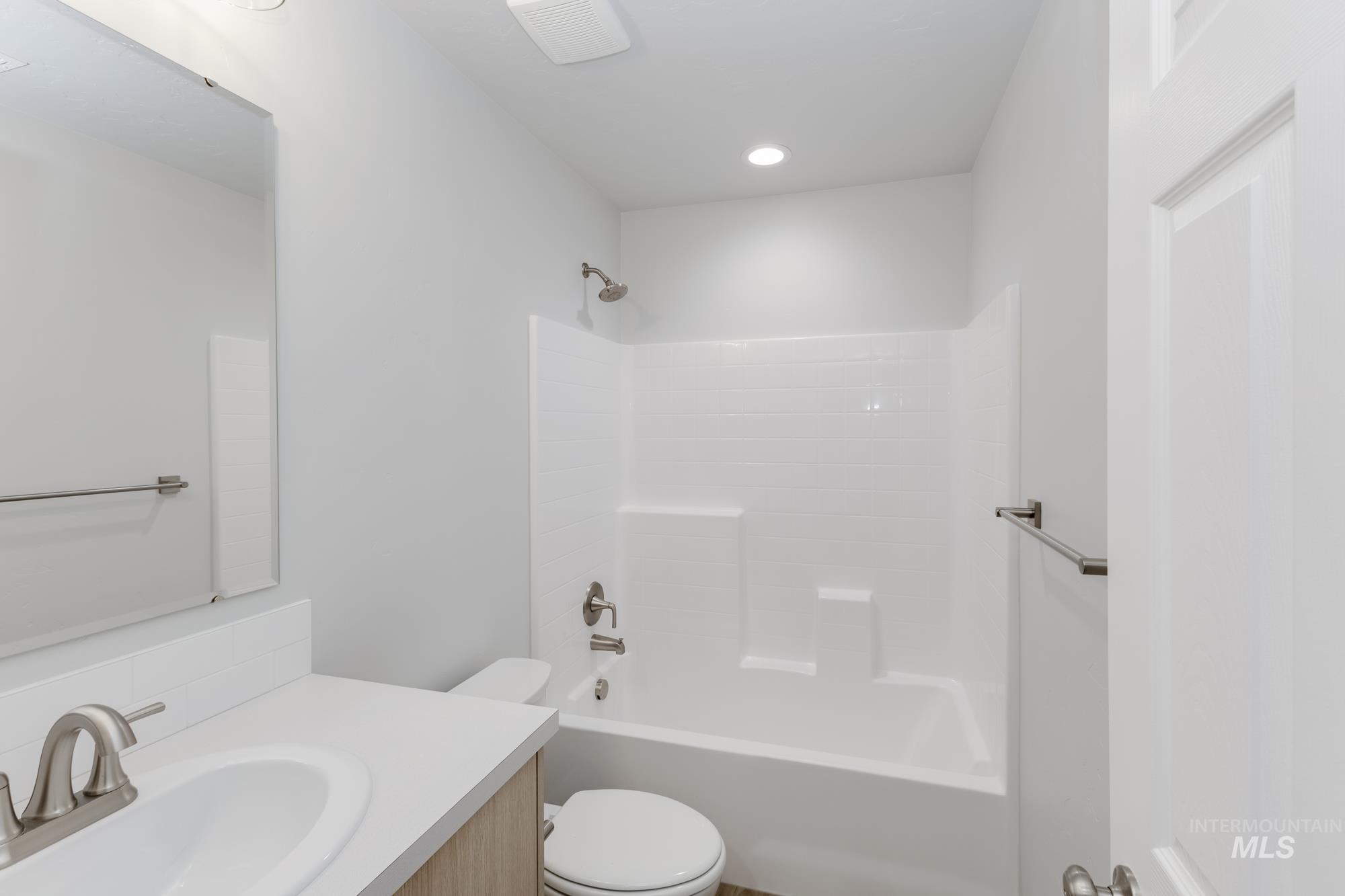 Bathroom with shower / washtub combination, vanity, and recessed lighting