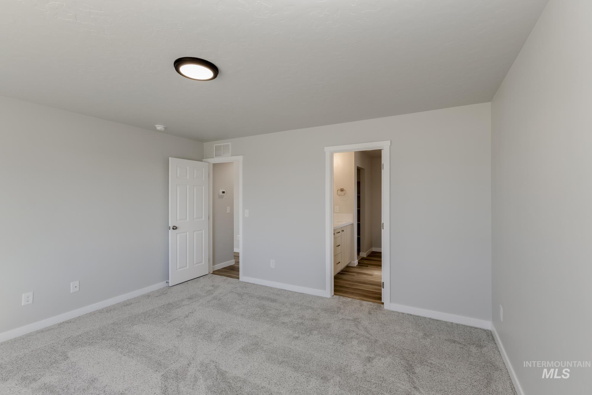 Unfurnished bedroom featuring light carpet and ensuite bath