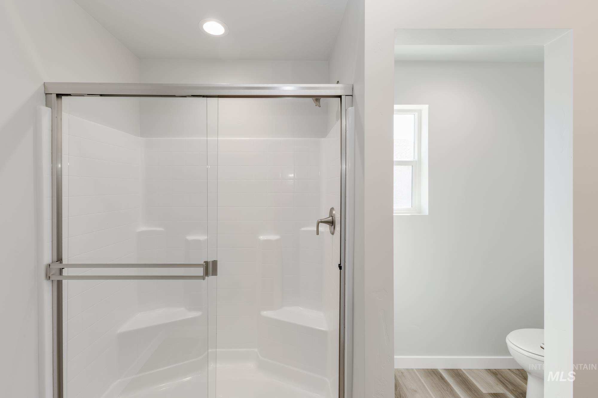 Full bathroom featuring a stall shower and light wood-type flooring