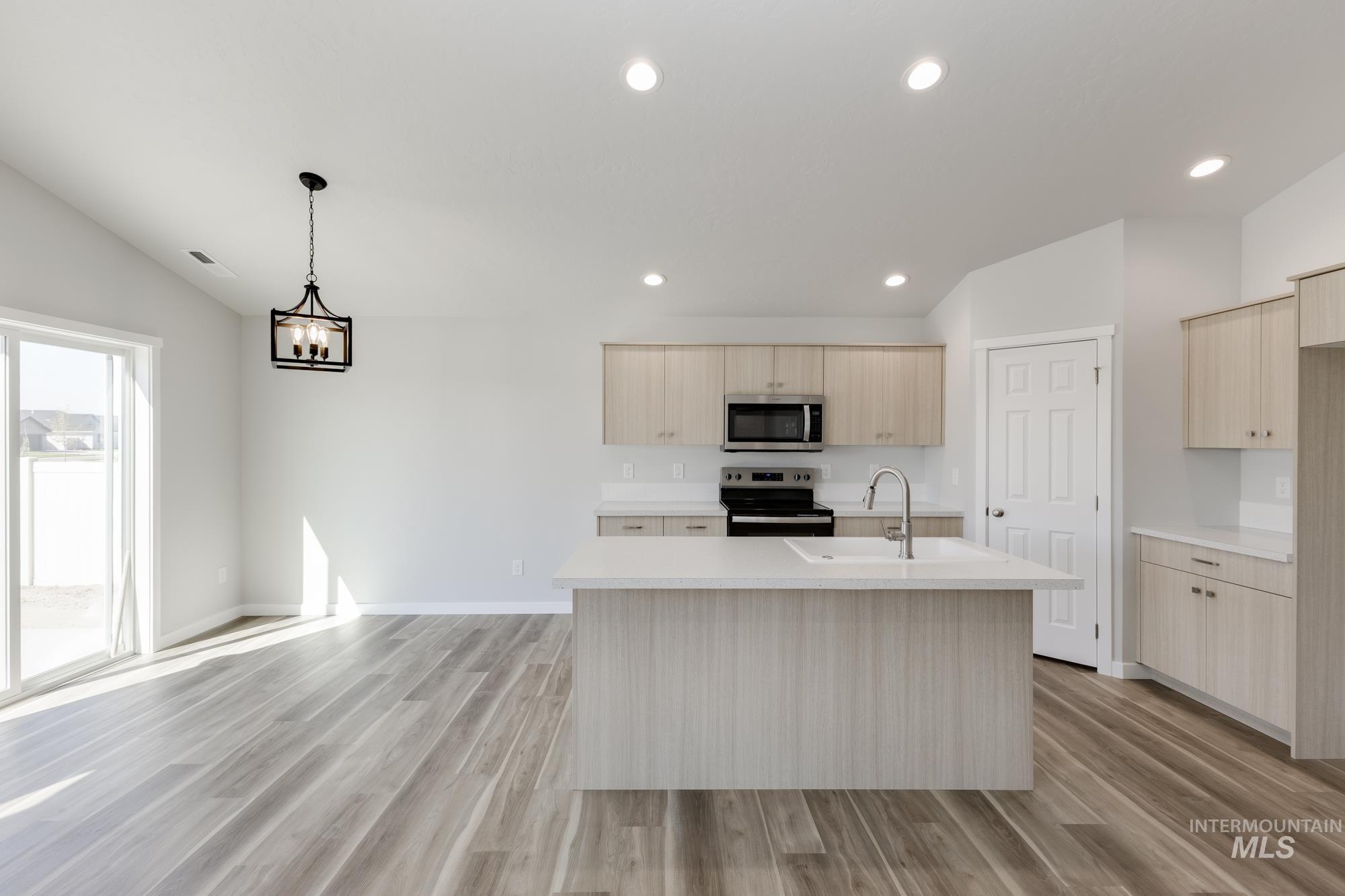 Kitchen featuring light brown cabinets, light wood-type flooring, a kitchen island with sink, stainless steel appliances, and recessed lighting