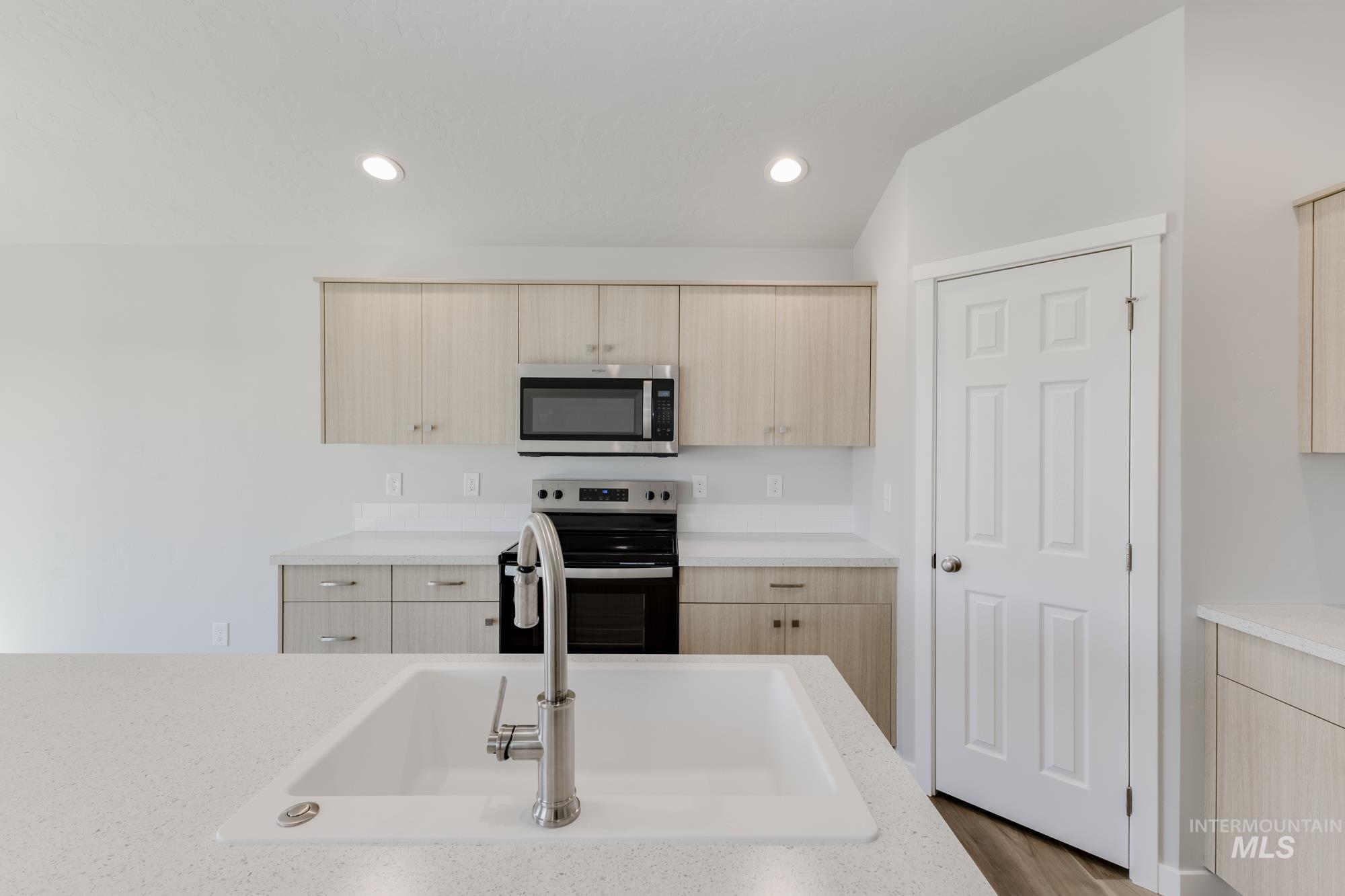 Kitchen with light brown cabinetry, stainless steel appliances, modern cabinets, recessed lighting, and light stone counters